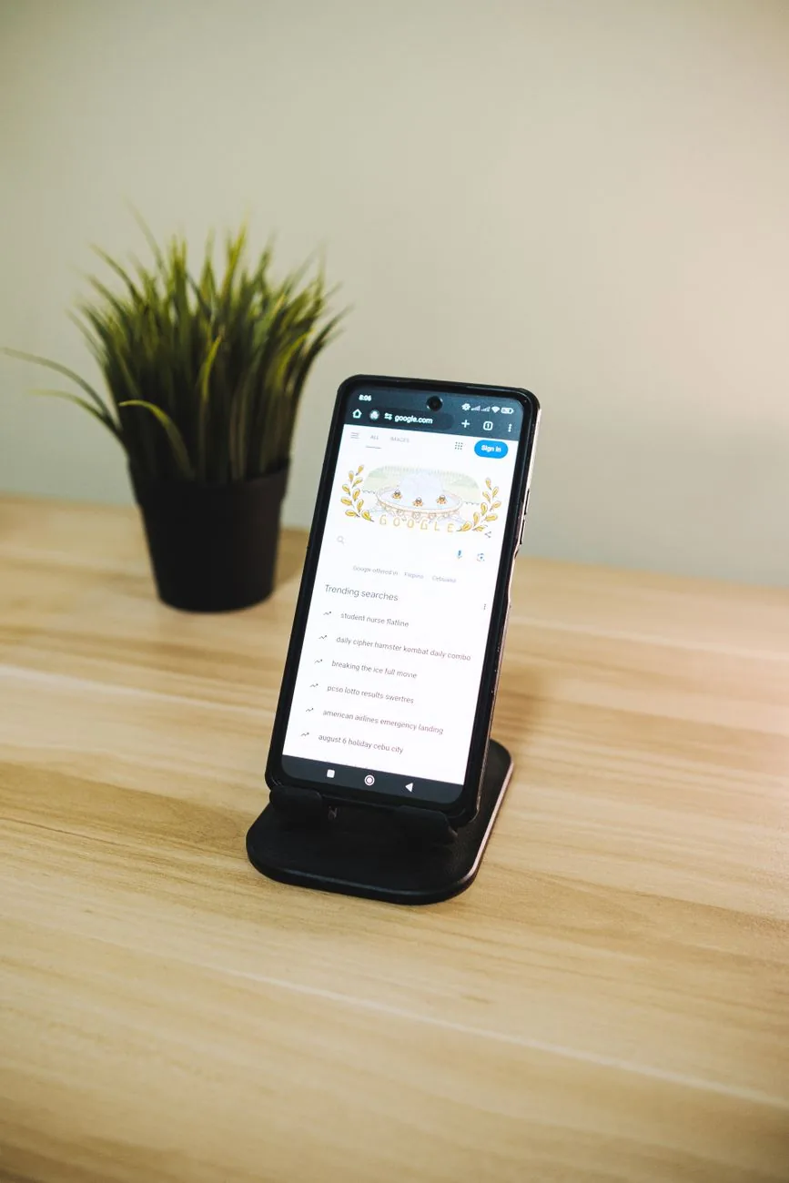 smartfon na drewnianym biurku obok rośliny doniczkowej — realme 12 poza naszym warsztatem — gdzie szukać pomocy