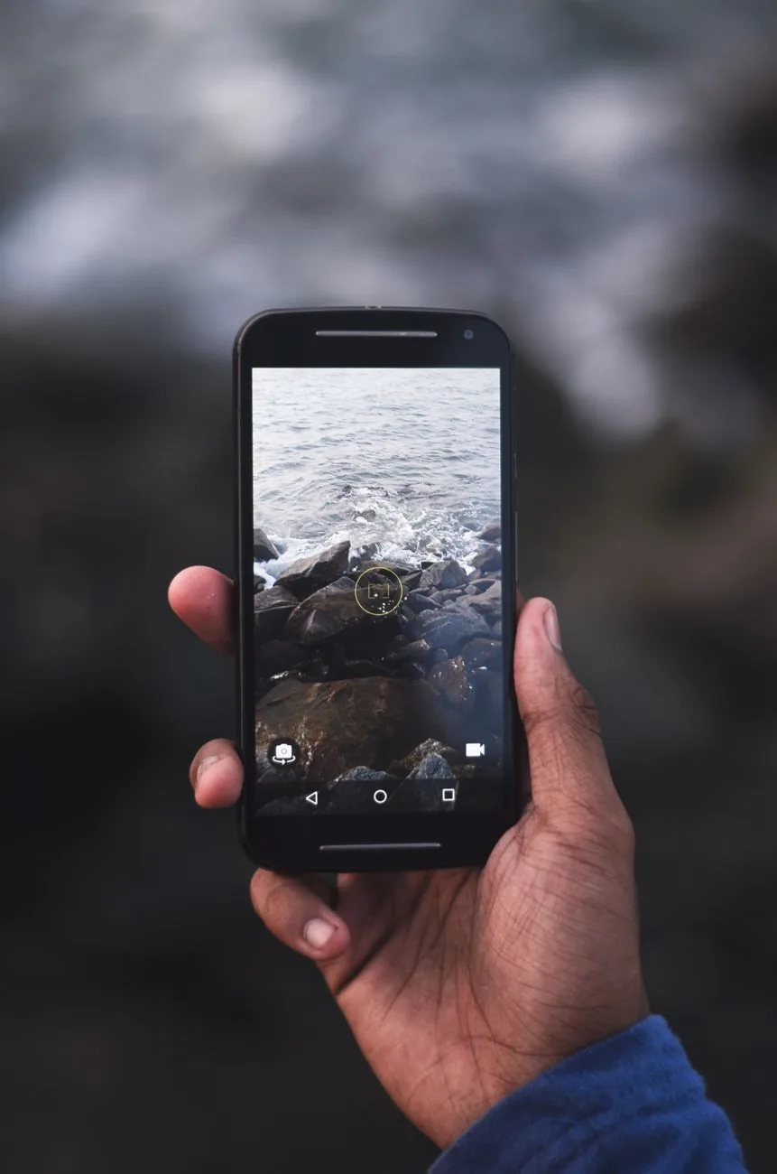 dłoń trzymająca smartfon na tle skalistego wybrzeża — realme 6 a zakres naszego serwisu — czym zajmujemy się zamiast