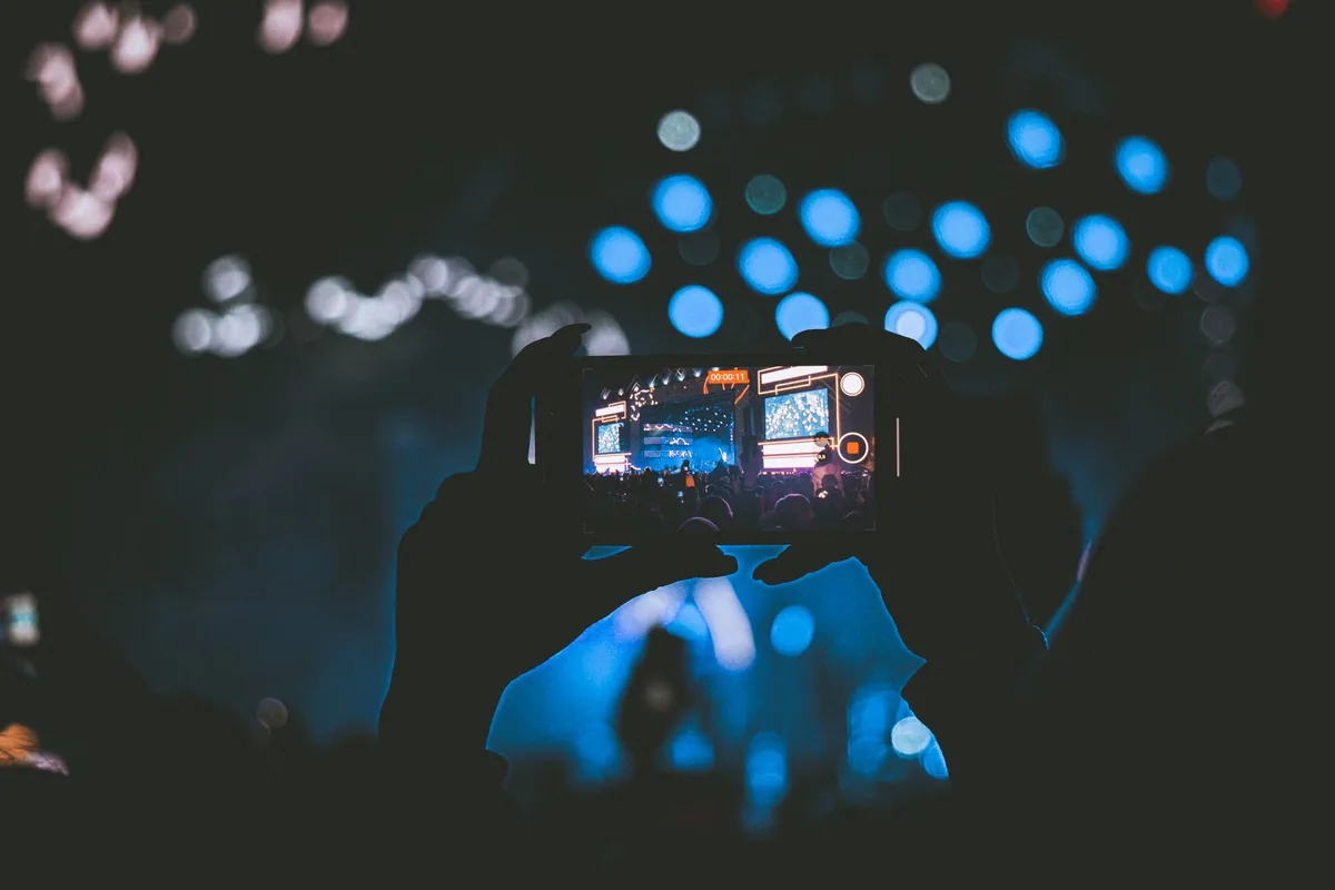 smartfon rejestrujący scenę koncertową ze światłami bokeh — realme 9i poza naszym warsztatem — gdzie szukać pomocy