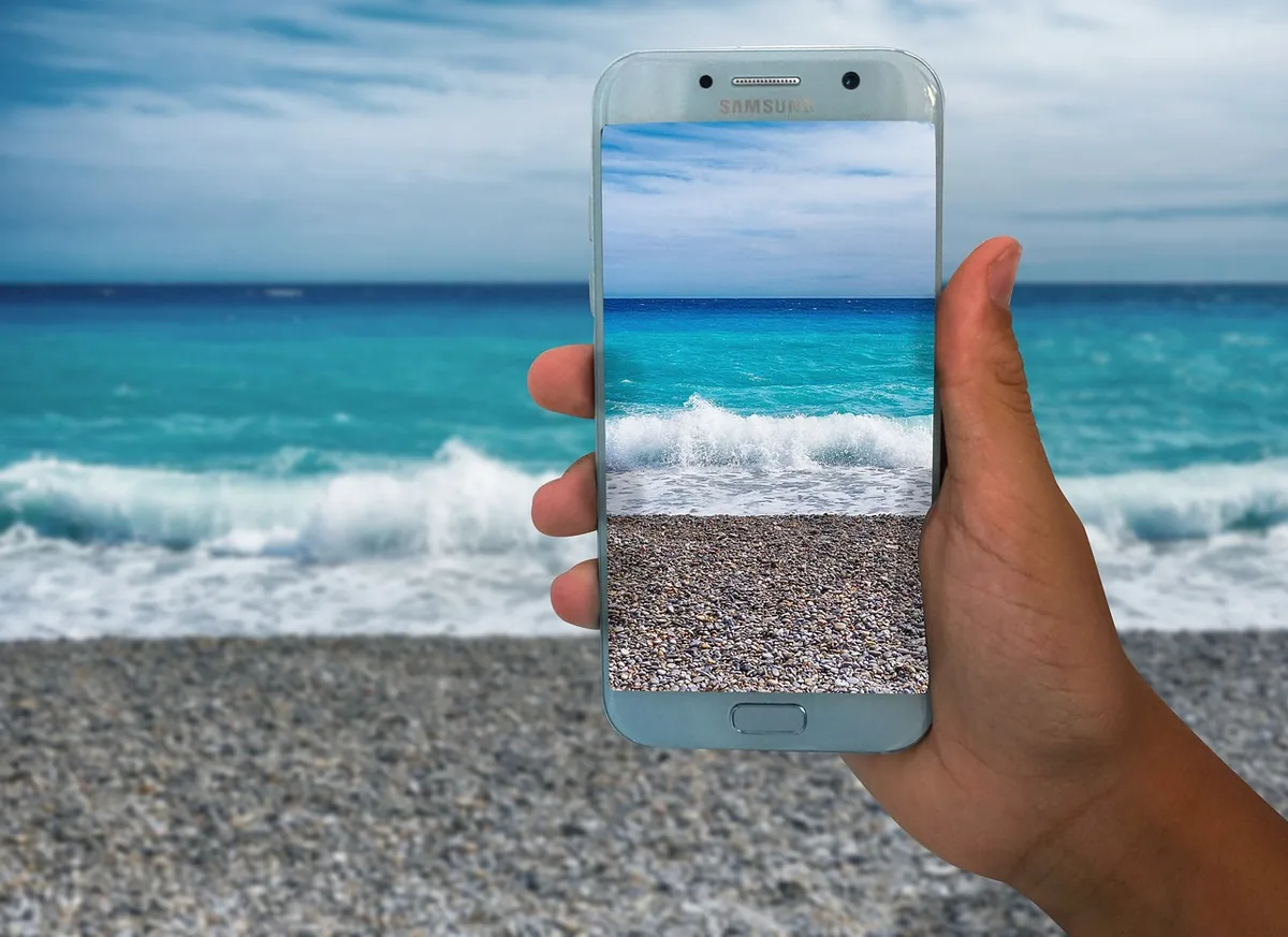 dłoń ze smartfonem na tle morskiego krajobrazu — realme C35 a zakres naszego serwisu — czym zajmujemy się zamiast