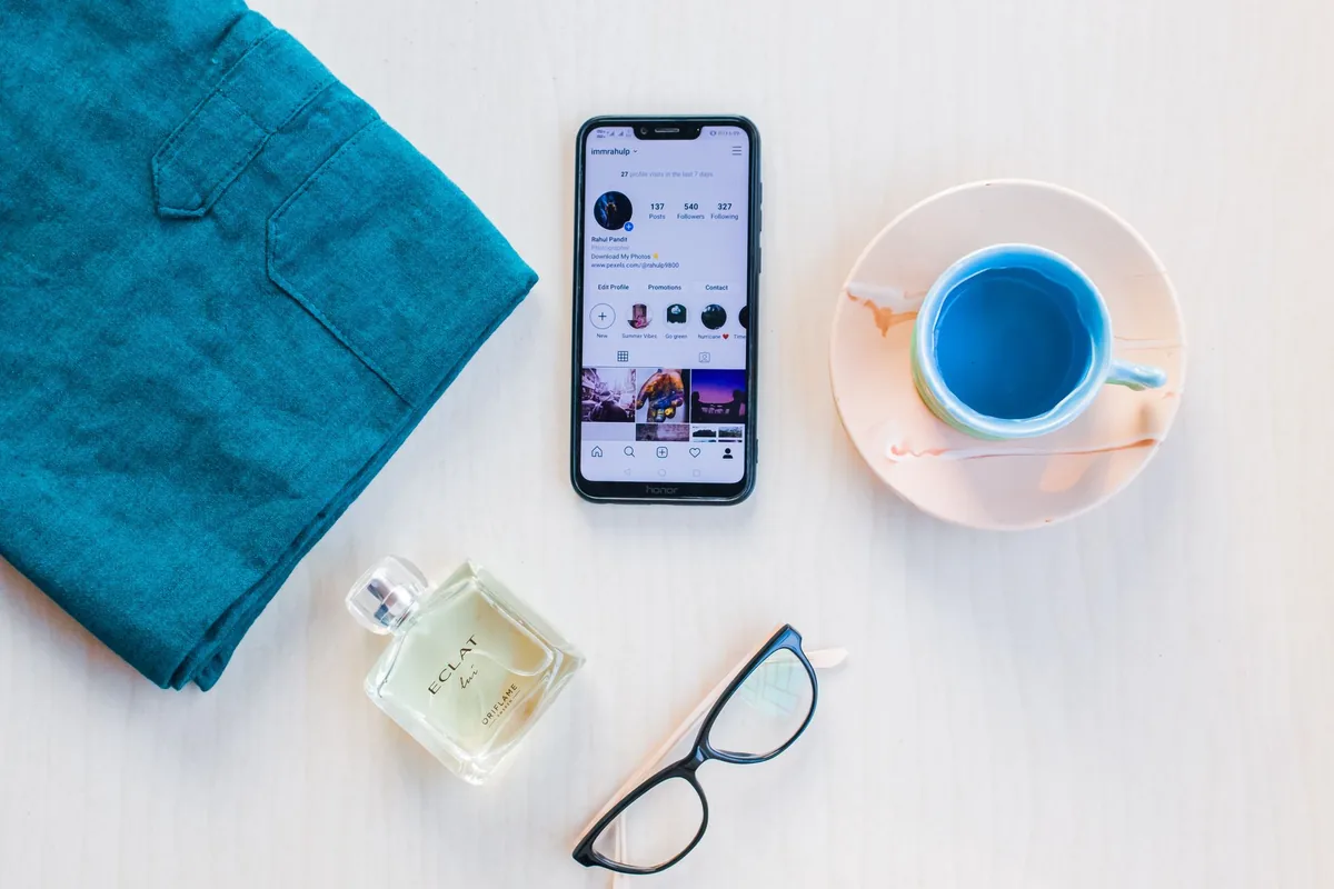 telefon komórkowy obok kubka z napojem i flakonu perfum — realme GT 3 w zgłoszeniu — jak odpowiadamy i co radzimy