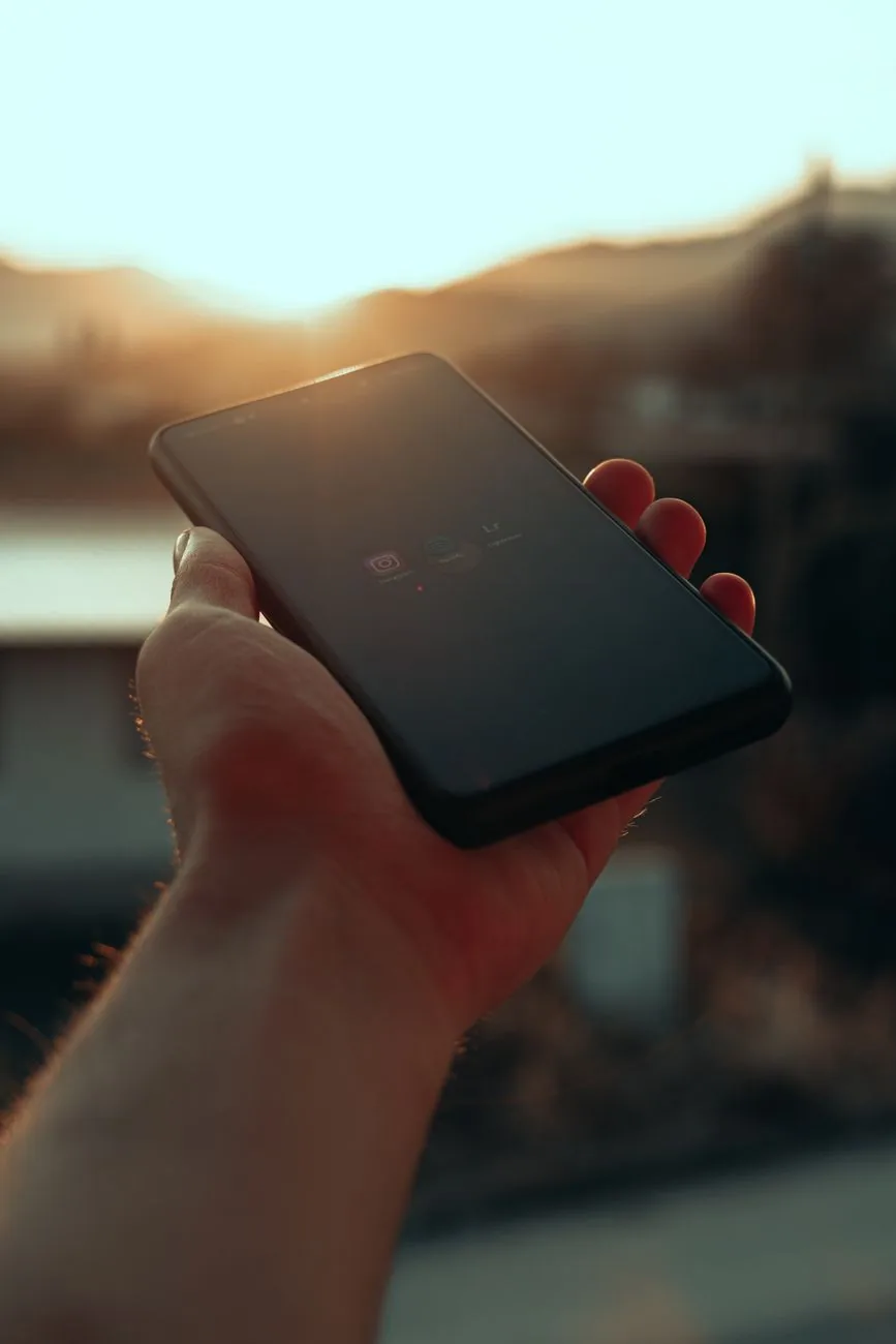 dłoń trzymająca smartfon na tle zachodzącego słońca — realme Narzo 60 w zgłoszeniu — jak odpowiadamy i co radzimy