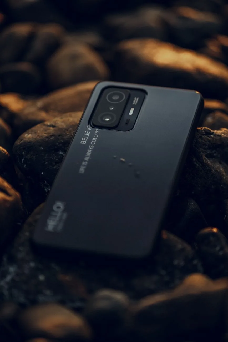 smartfon leżący na mokrych kamieniach o zmierzchu — Redmi 13 w zgłoszeniu — jak odpowiadamy i co radzimy