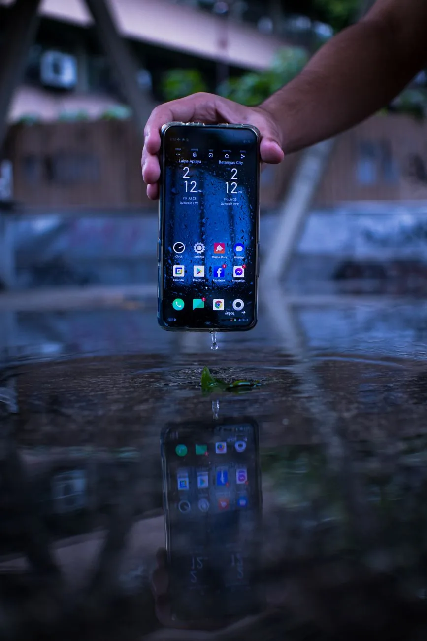 dłoń trzymająca smartfon nad mokrą powierzchnią — Redmi 14C poza naszym warsztatem — gdzie szukać pomocy