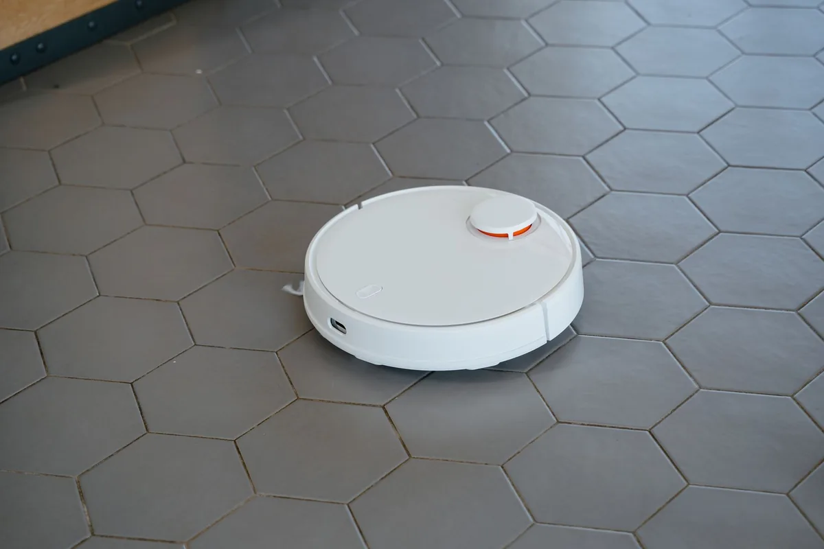 biały robot sprzątający na podłodze z sześciokątnych płytek — Roborock S8 poza naszym warsztatem — gdzie szukać pomocy