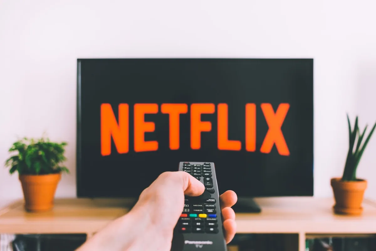 dłoń trzymająca pilot przed ekranem z aplikacją netflix — Samsung Crystal UHD AU7100 w zgłoszeniu — jak odpowiadamy i co radzimy