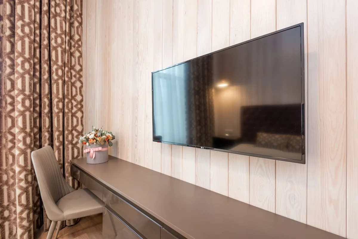 nowoczesny telewizor w przytulnej sypialni obok bukietu kwiatów — Samsung Crystal UHD DU7100 w zgłoszeniu — jak odpowiadamy i co radzimy