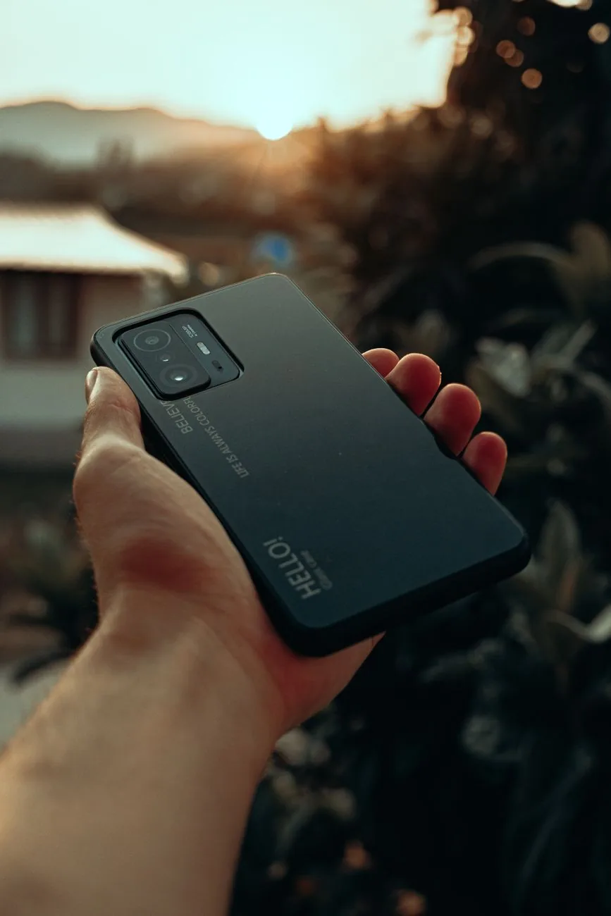 dłoń trzymająca smartfon na zewnątrz o zachodzie słońca — Samsung Galaxy A03 a zakres naszego serwisu — czym zajmujemy się zamiast
