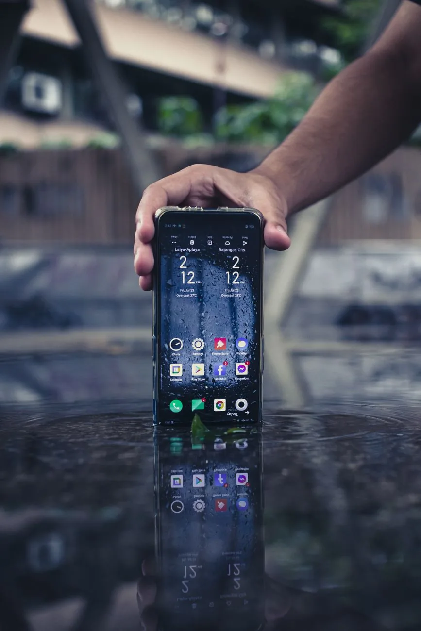 dłoń trzymająca smartfon z odbiciem w kałuży wody — Samsung Galaxy A04e w zgłoszeniu — jak odpowiadamy i co radzimy