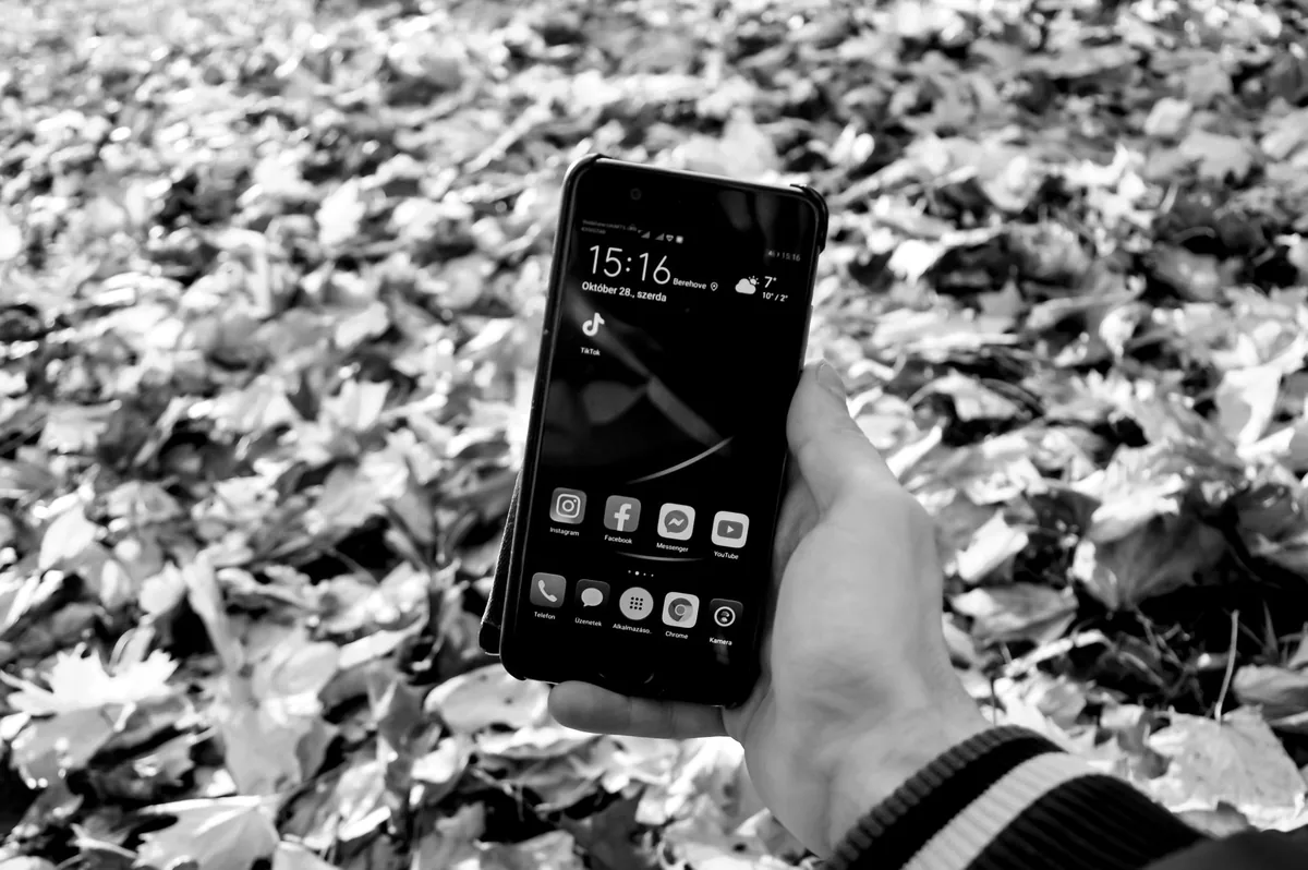 dłoń trzymająca smartfon wśród opadłych liści — Samsung Galaxy A14 5G w zgłoszeniu — jak odpowiadamy i co radzimy