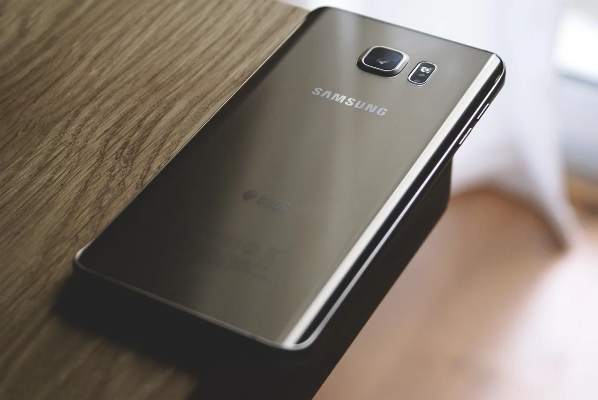 czarny smartfon Samsung leżący na drewnianym stole — Samsung Galaxy A14 w zgłoszeniu — jak odpowiadamy i co radzimy