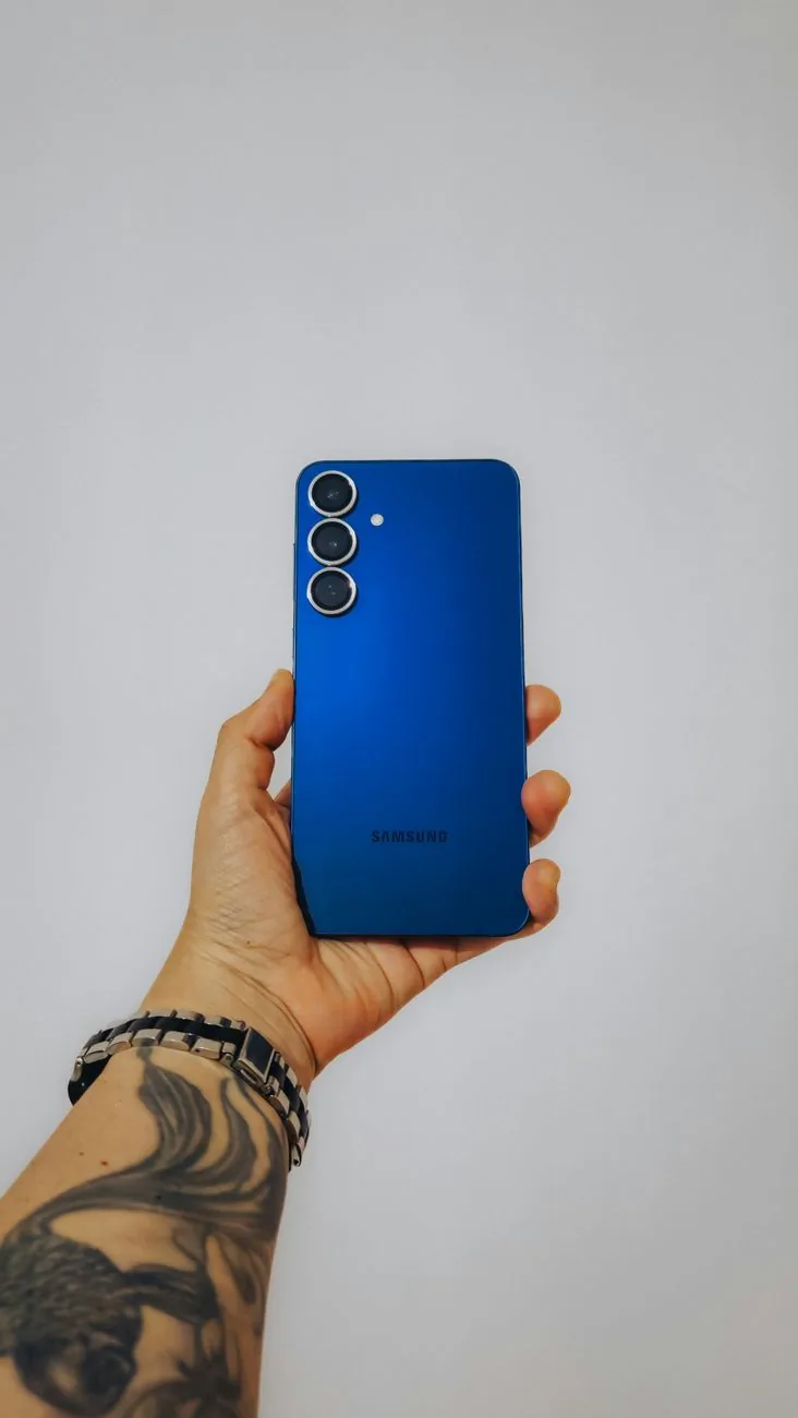 dłoń z tatuażami trzymająca niebieski smartfon — Samsung Galaxy A24 a zakres naszego serwisu — czym zajmujemy się zamiast