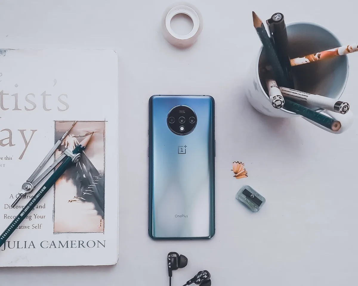 smartfon, szklanka z ołówkami i książka na białym stole — Samsung Galaxy A71 5G — czego przy tym sprzęcie nie zrobimy