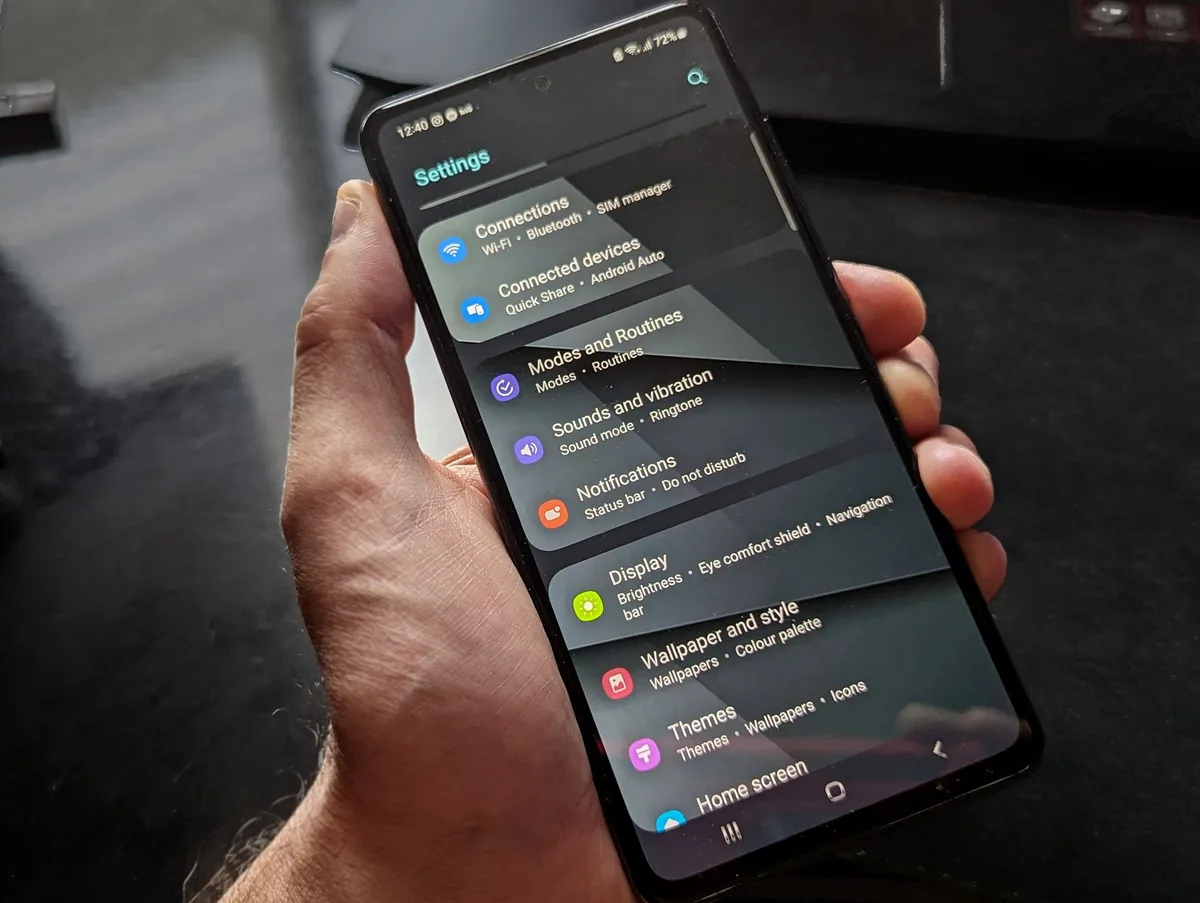 dłoń trzymająca smartfon z otwartym menu ustawień — Samsung Galaxy A71 poza naszym warsztatem — gdzie szukać pomocy