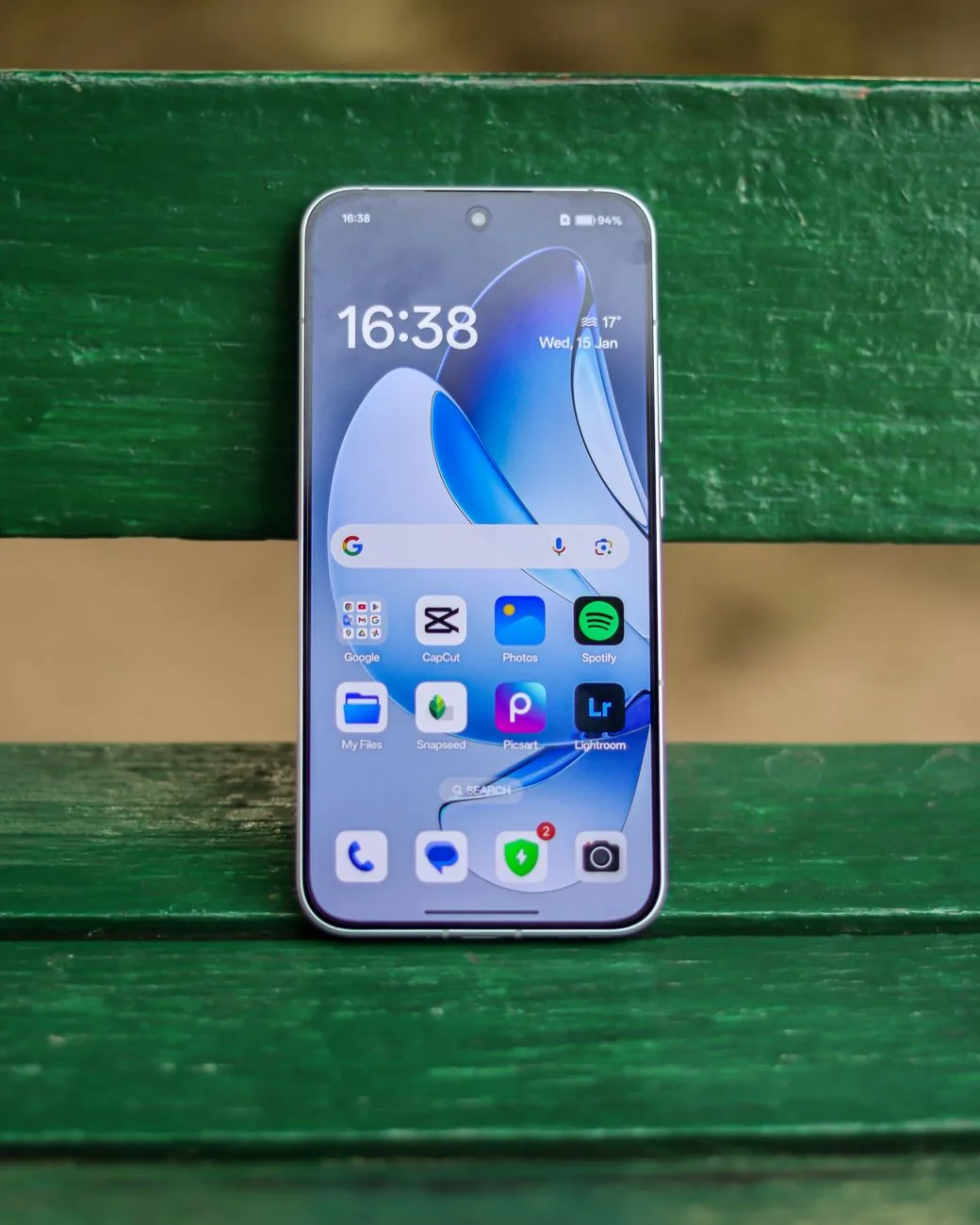 smartfon z włączonymi aplikacjami leżący na zielonej ławce — Samsung Galaxy Note 20 a zakres naszego serwisu — czym zajmujemy się zamiast