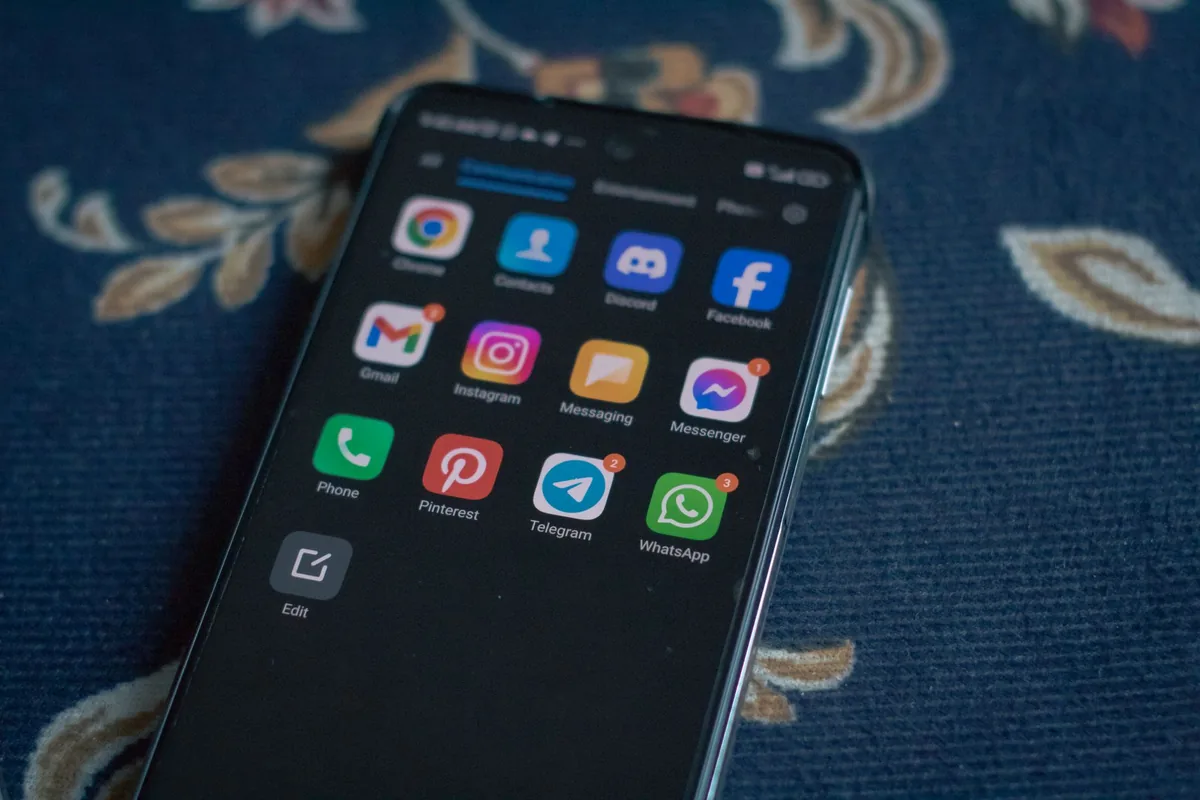 smartfon z aplikacjami społecznościowymi na tkaninie w kwiaty — Samsung Galaxy S24 a zakres naszego serwisu — czym zajmujemy się zamiast