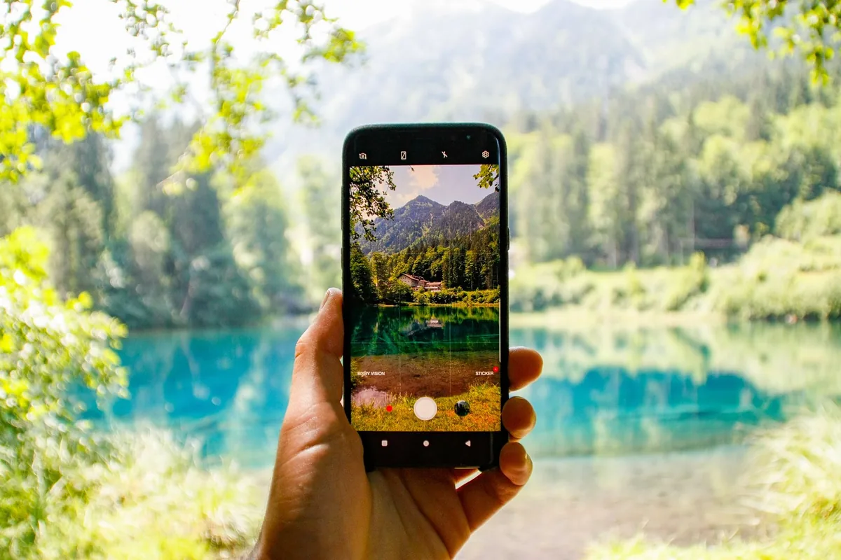 dłoń trzymająca smartfon skierowany na górskie jezioro — Samsung Galaxy S25 Edge w zgłoszeniu — jak odpowiadamy i co radzimy