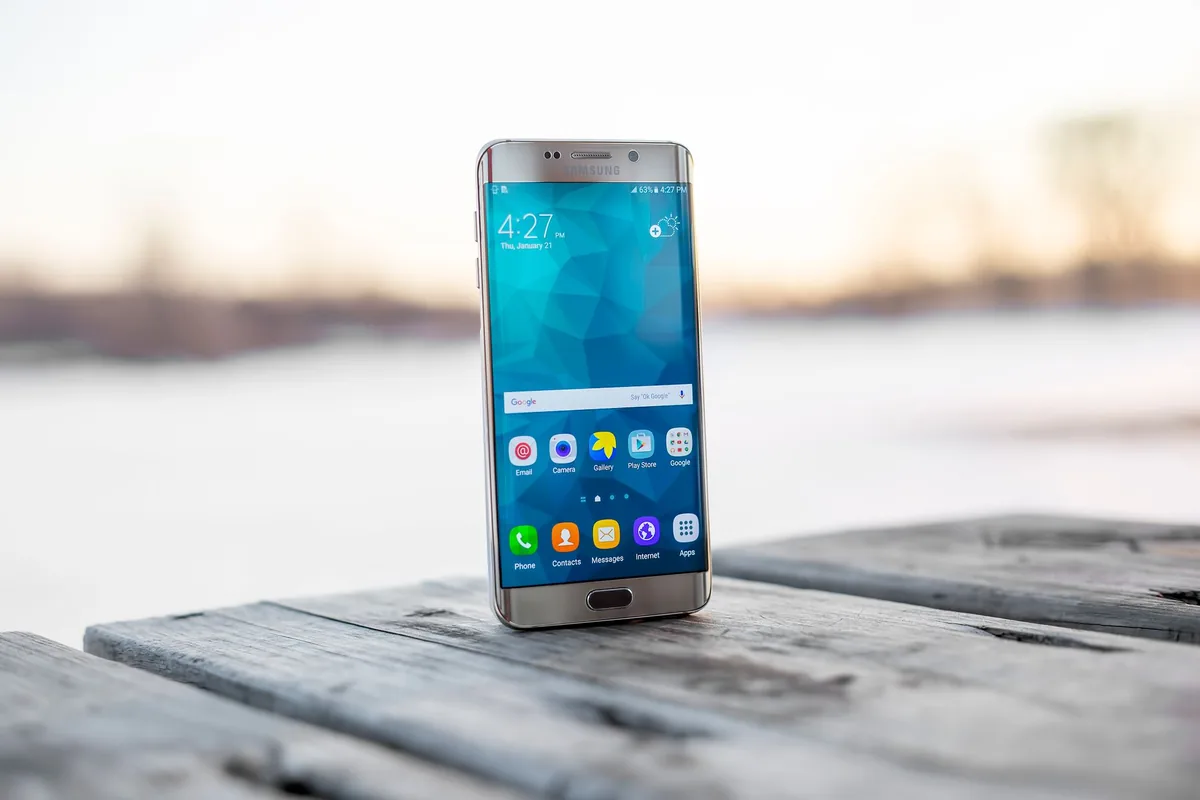 smartfon Samsung na drewnianej powierzchni na zewnątrz o zachodzie słońca — Samsung Galaxy S9 a zakres naszego serwisu — czym zajmujemy się zamiast