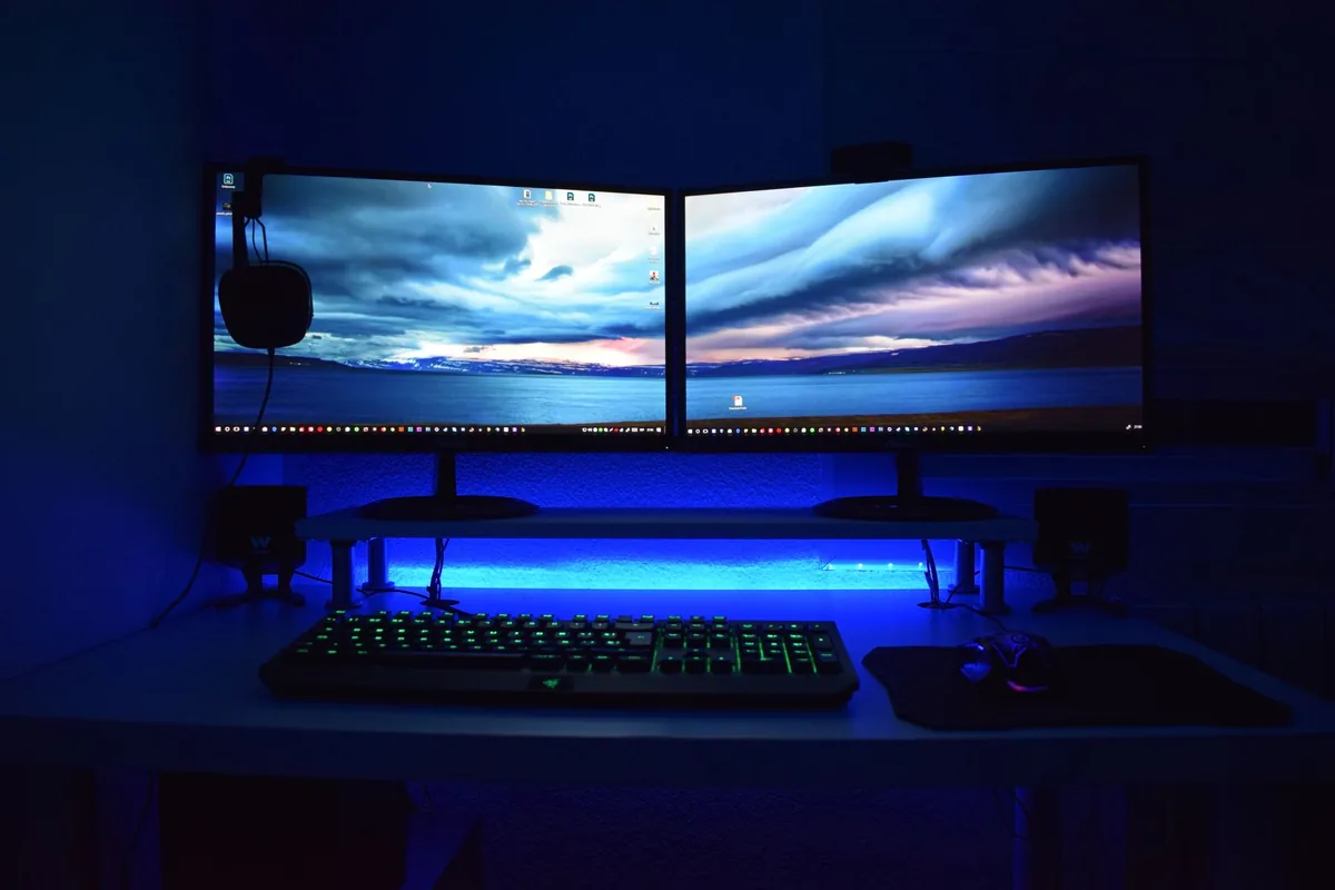 dwa monitory z niebieskim podświetleniem na biurku gracza — Samsung Odyssey G5 a zakres naszego serwisu — czym zajmujemy się zamiast
