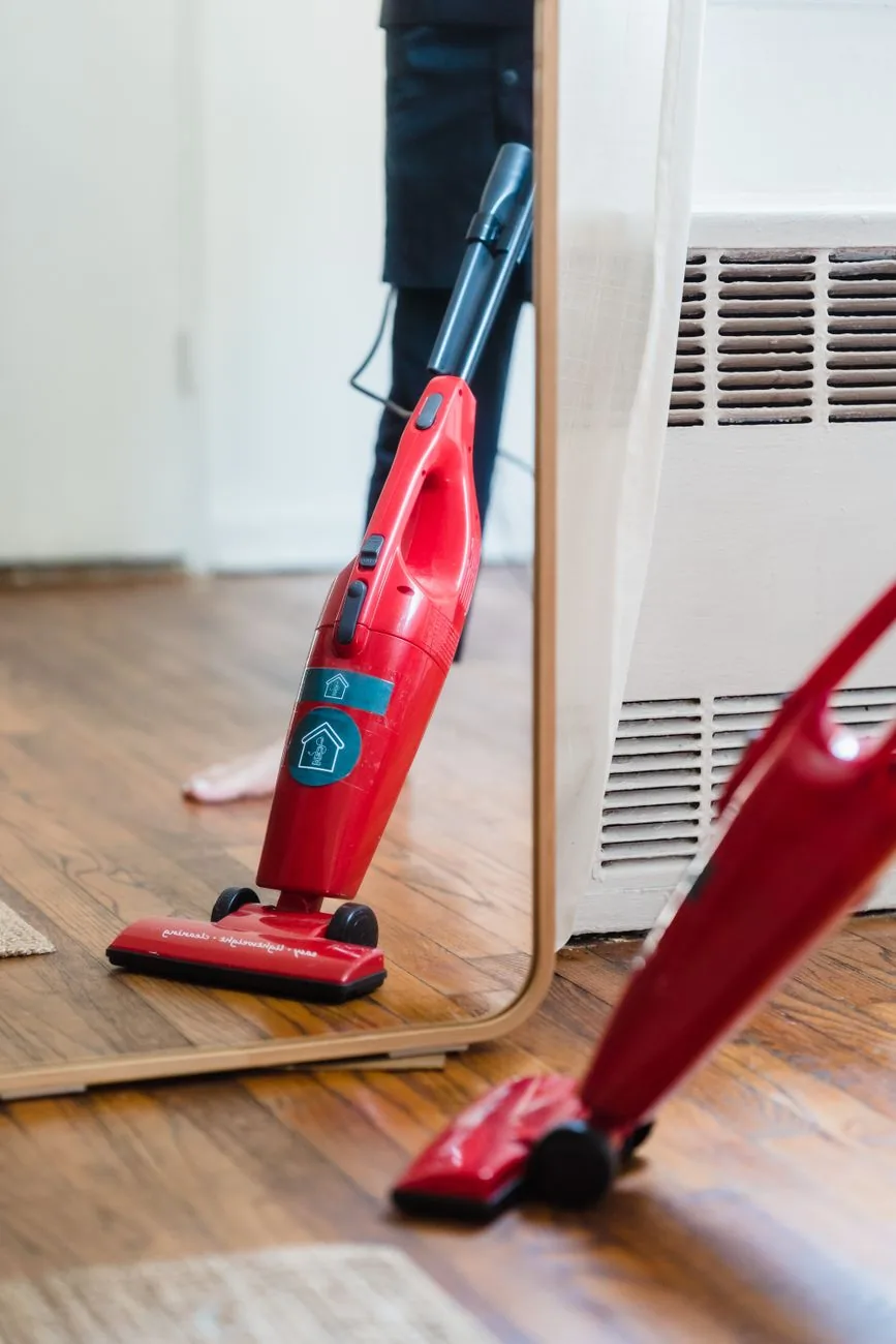 czerwony odkurzacz na drewnianej podłodze przy lustrze — Samsung PowerBot VR7000 a zakres naszego serwisu — czym zajmujemy się zamiast