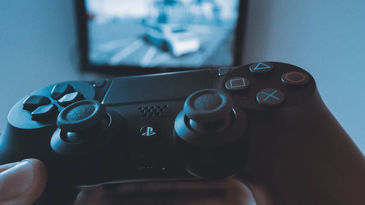 dłoń z bezprzewodowym kontrolerem przed ekranem telewizora — Snakebyte GamePad 4S w zgłoszeniu — jak odpowiadamy i co radzimy