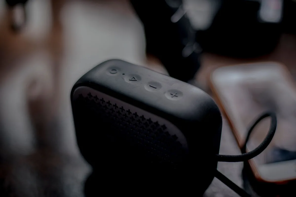 głośnik bezprzewodowy obok smartfona na drewnianym blacie — Sonos Sub Mini w zgłoszeniu — jak odpowiadamy i co radzimy