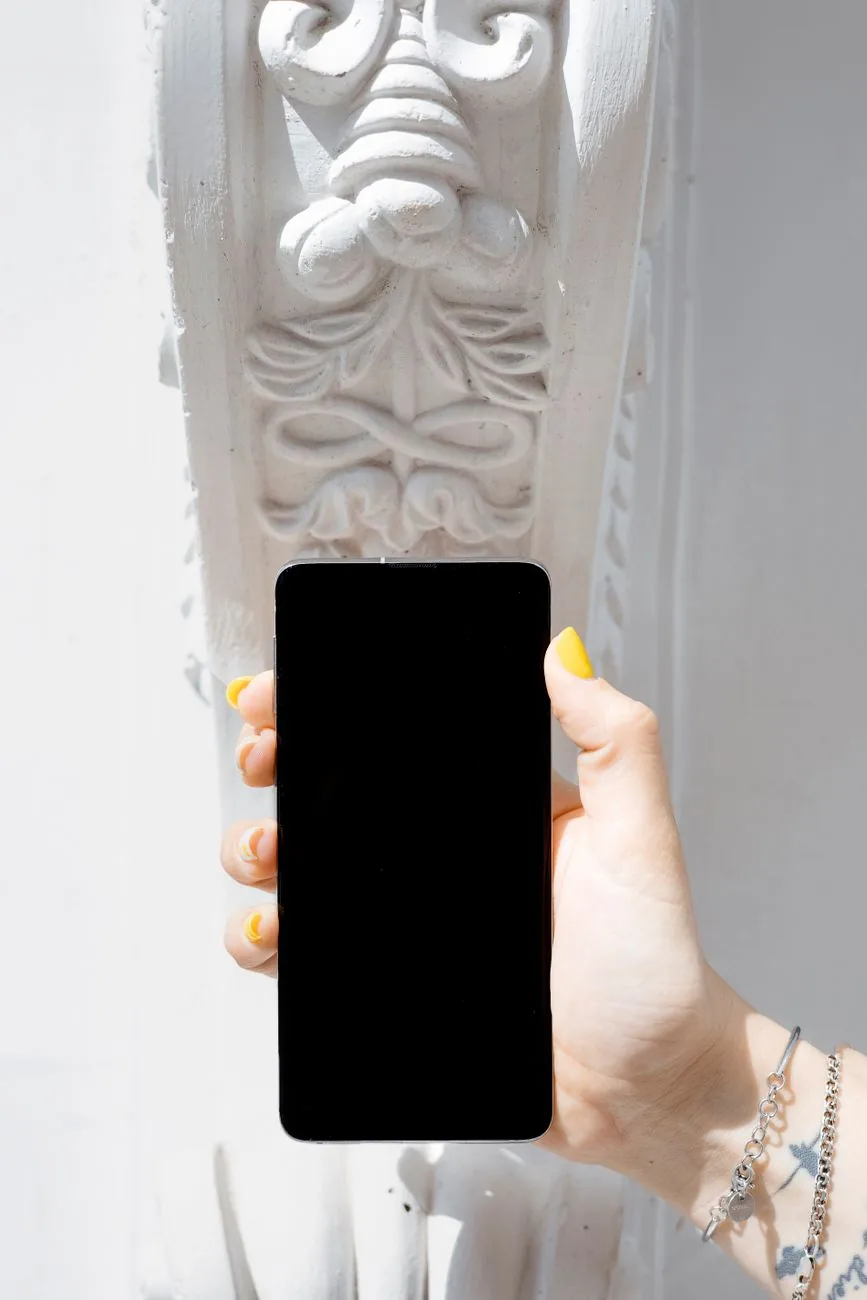 dłoń trzymająca telefon komórkowy na tle rzeźbionej białej ściany — Sony Xperia 5 IV — czego przy tym sprzęcie nie zrobimy