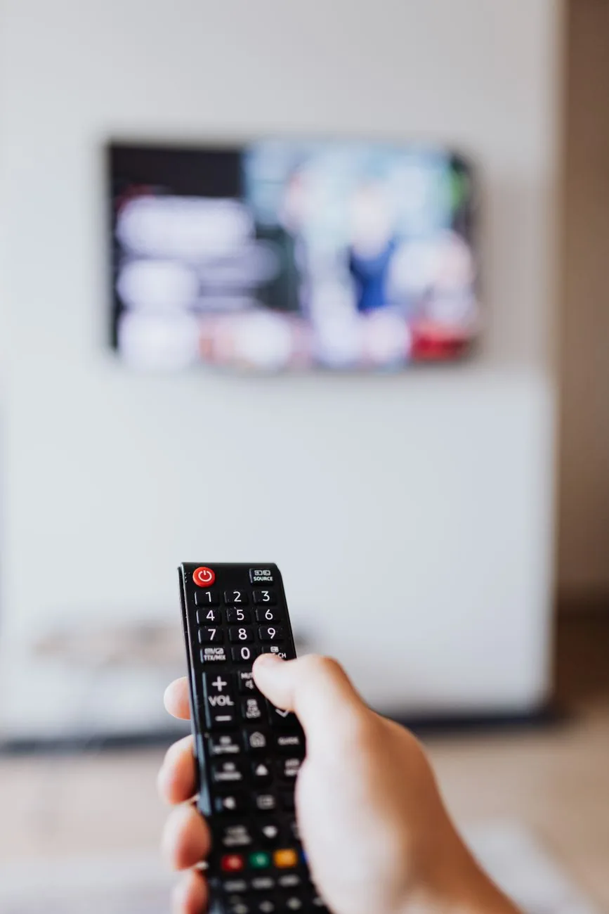 dłoń obsługująca pilot przed ekranem telewizora — Toshiba 43UV2363DG poza naszym warsztatem — gdzie szukać pomocy