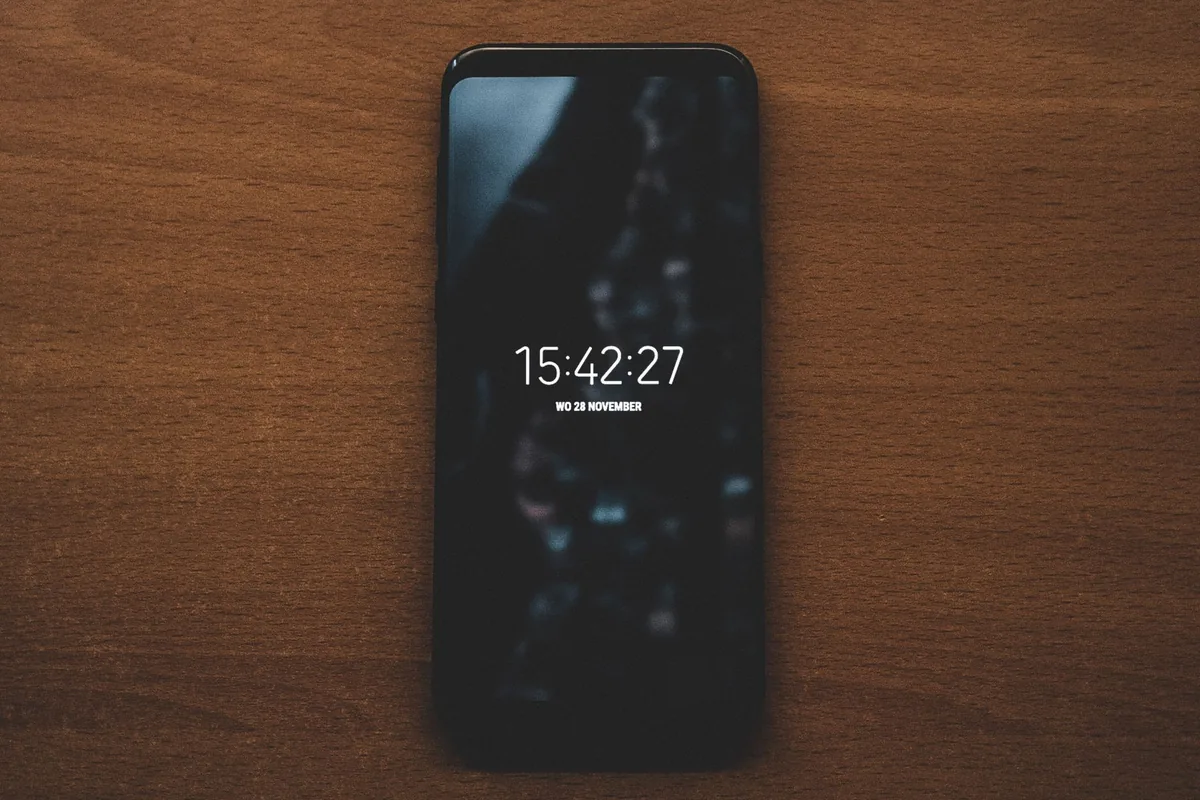 smartfon z zegarem na drewnianym blacie — Xiaomi 12 Lite a zakres naszego serwisu — czym zajmujemy się zamiast