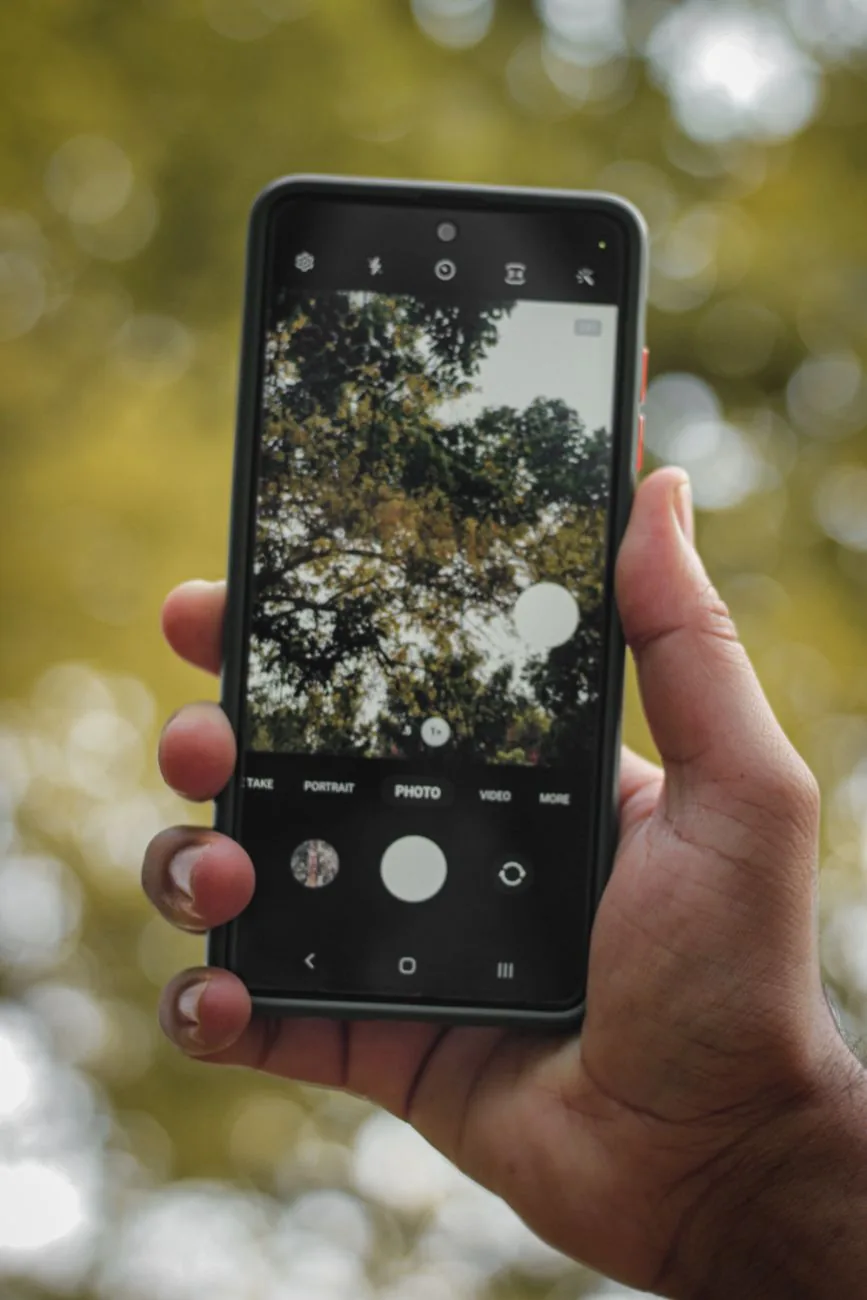 dłoń trzymająca smartfon na tle drzew — Xiaomi 12 w zgłoszeniu — jak odpowiadamy i co radzimy