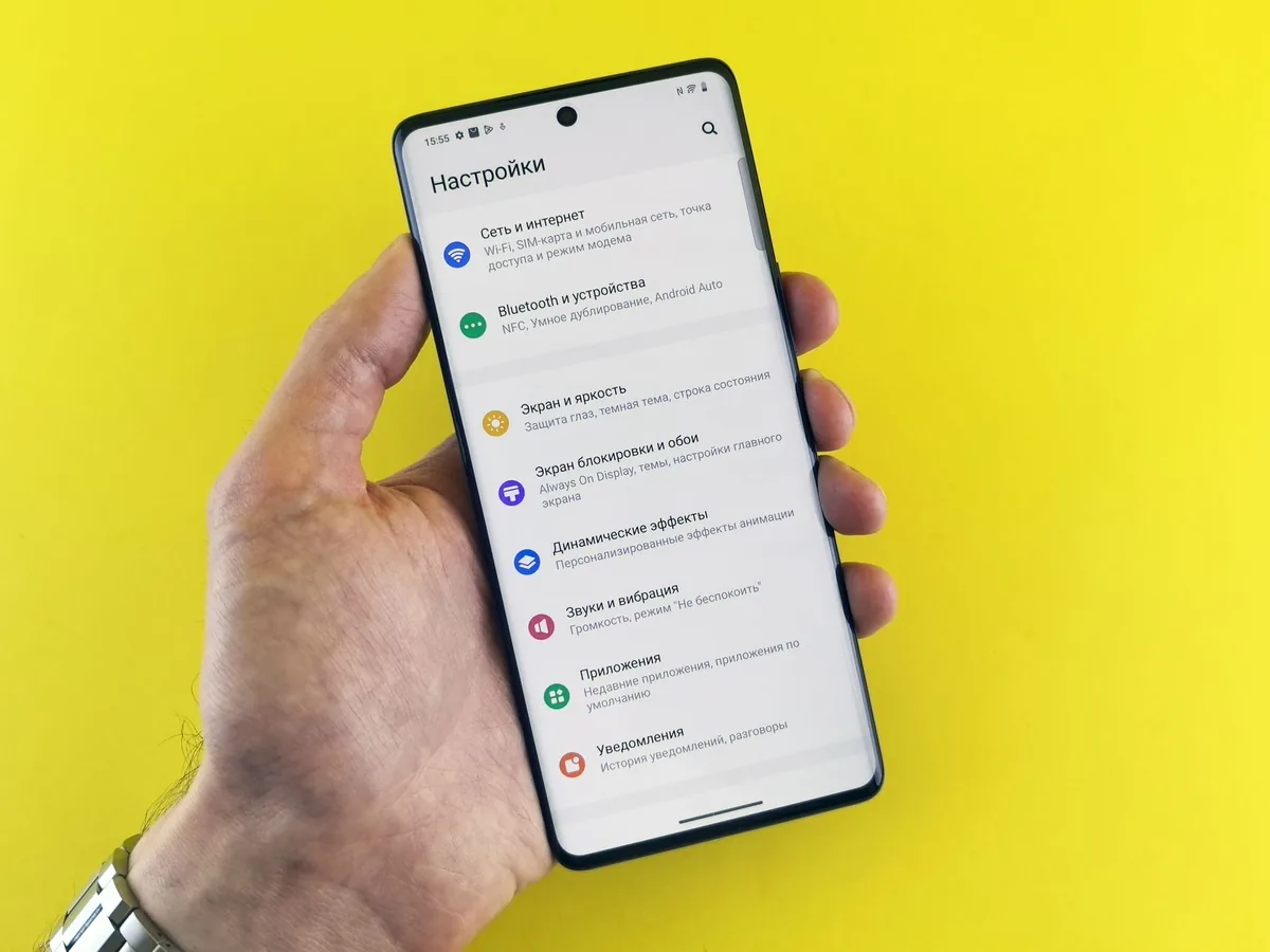 dłoń trzymająca smartfon z menu ustawień na żółtym tle — Xiaomi Mi Note 10 a zakres naszego serwisu — czym zajmujemy się zamiast
