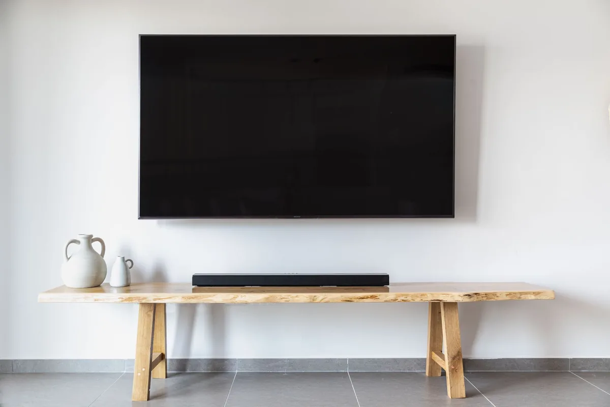 telewizor z płaskim ekranem na ścianie nad konsolą — Xiaomi TV A Pro a zakres naszego serwisu — czym zajmujemy się zamiast