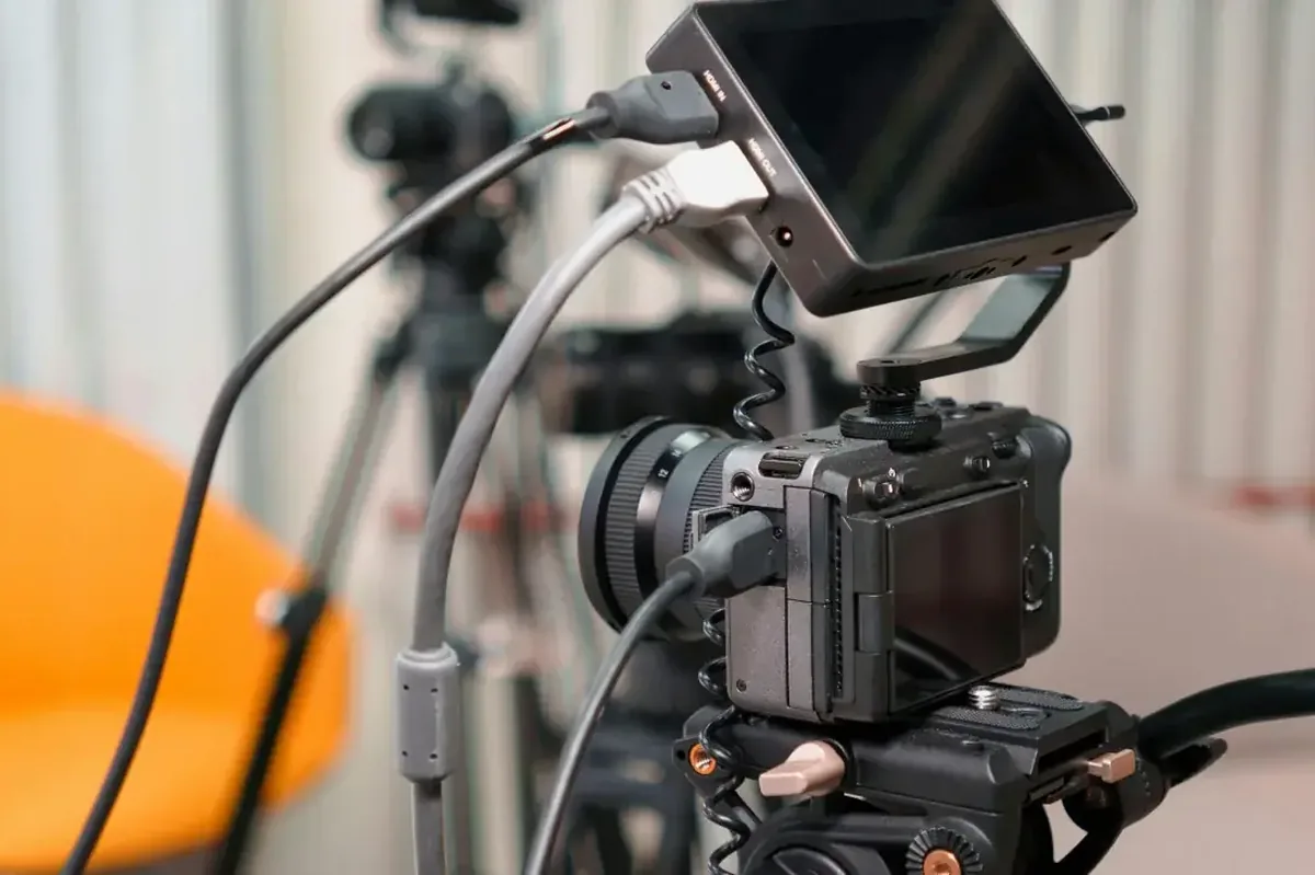 Aparat filmowy z podłączonymi kablami i zewnętrznym monitorem na statywie