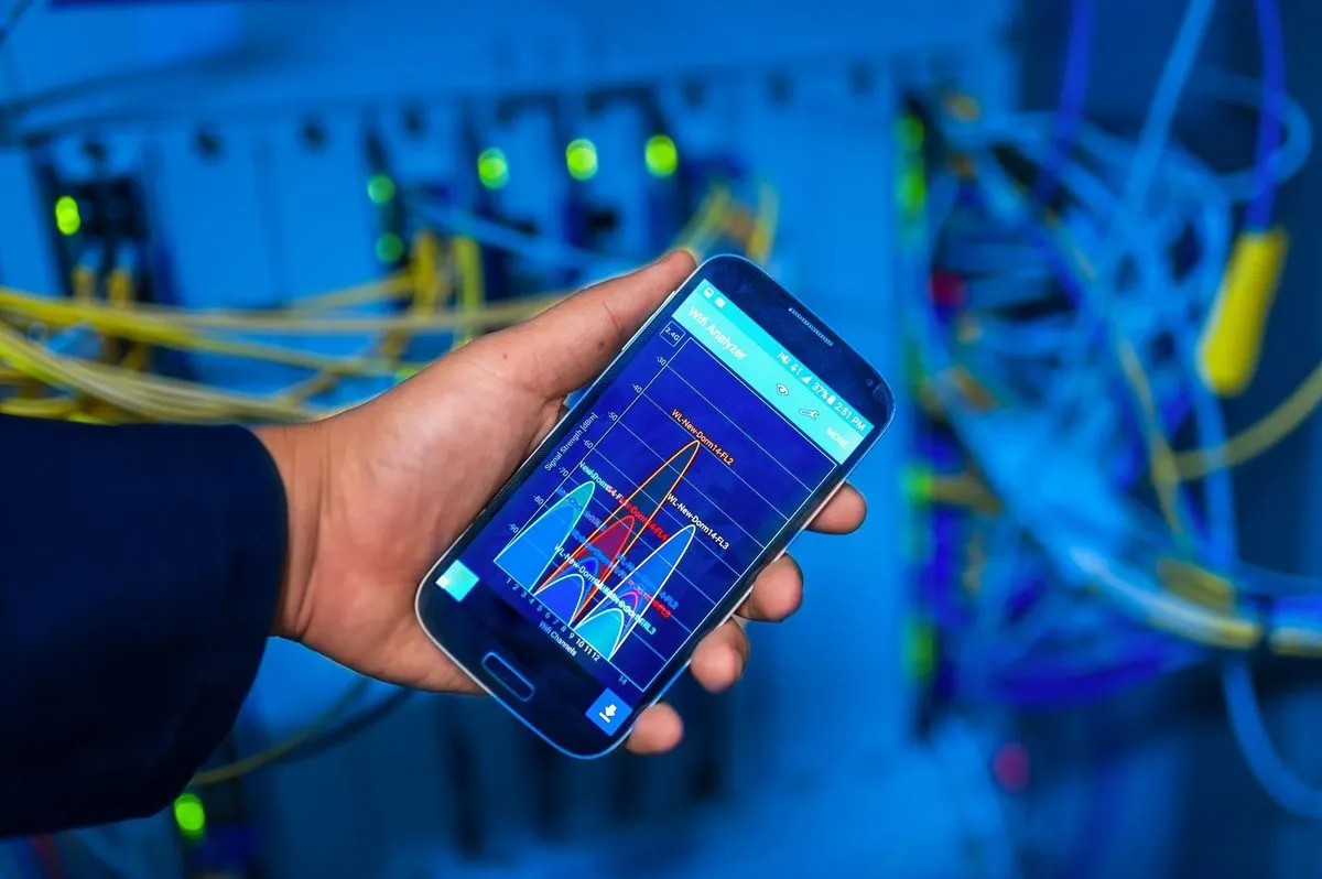 Dłoń trzymająca telefon z diagramem sieci na tle okablowania serwerowego — Microsoft Intune — zarządzanie urządzeniami firmowymi