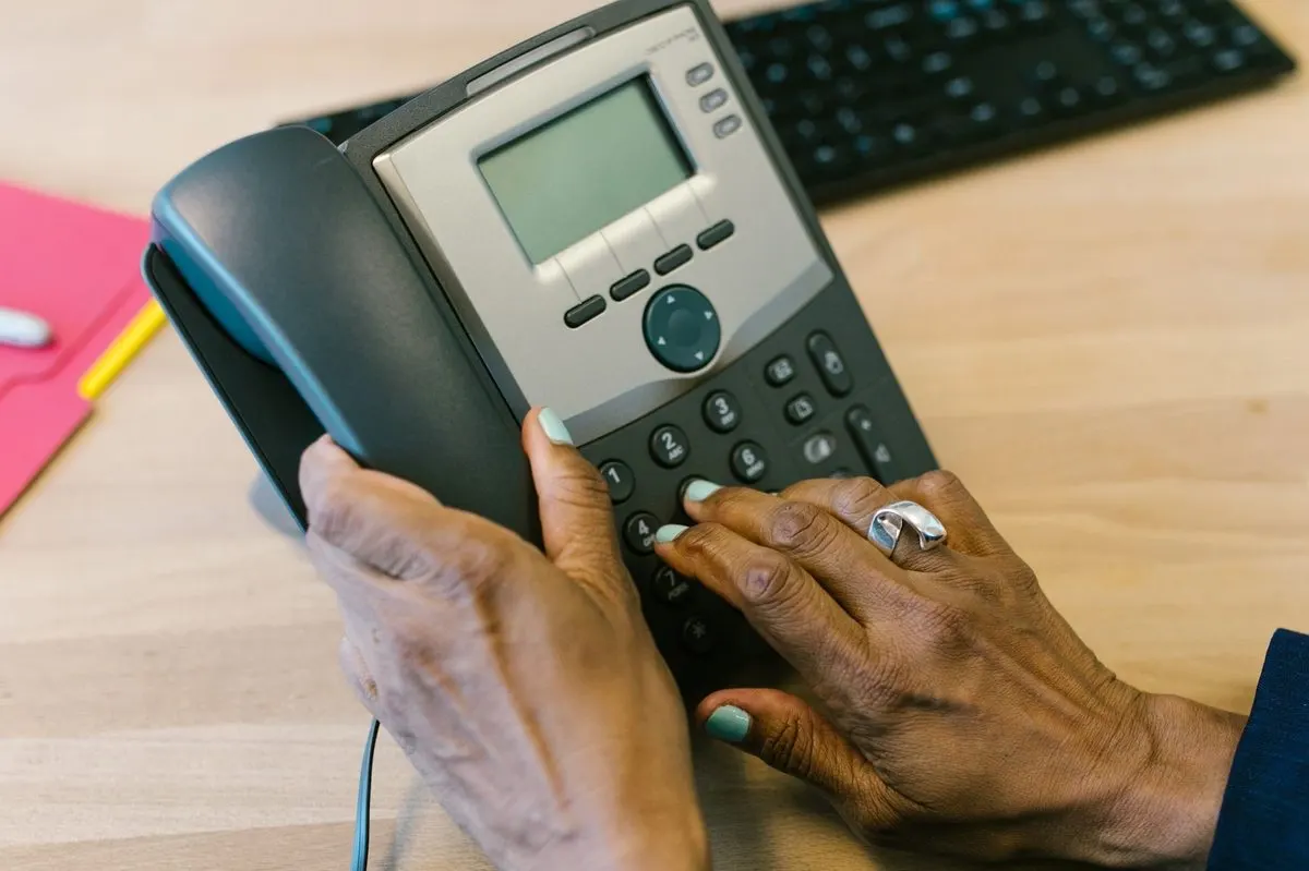 Dłoń wybierająca numer na biurowym telefonie IP — Serwis telefonów stacjonarnych i central telefonicznych biurowych