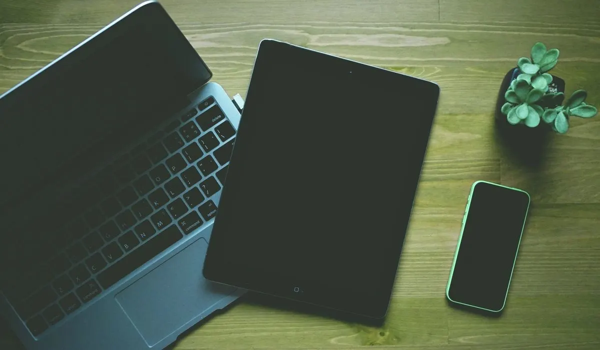Laptop, tablet i telefon rozłożone na biurku — Wdrażanie polityki BYOD — własne urządzenia pracowników