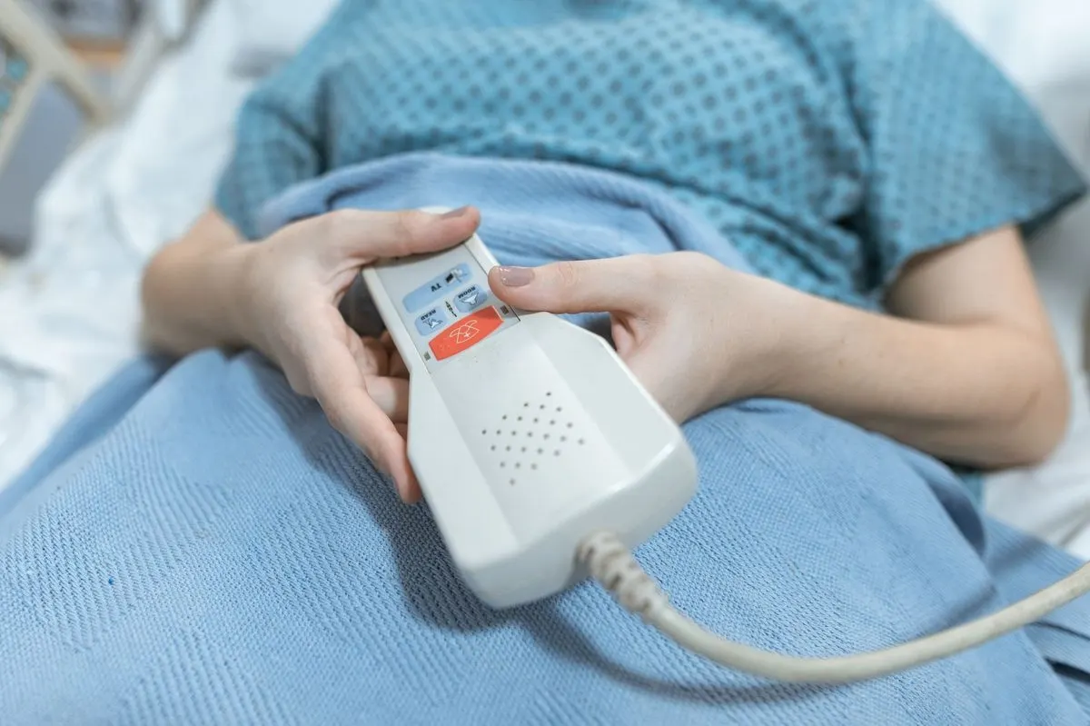 Dłoń trzymająca przycisk przywoławczy przy szpitalnym łóżku — Serwis systemów przywoławczych w placówkach medycznych