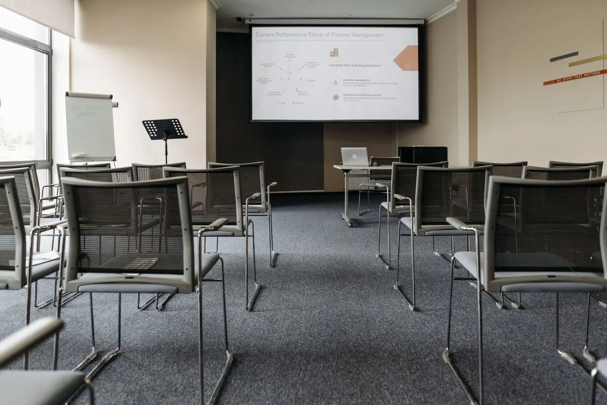Pusta sala szkoleniowa z ekranem projekcyjnym i rzędami krzeseł — Serwis systemów audio-wideo w salach szkoleniowych