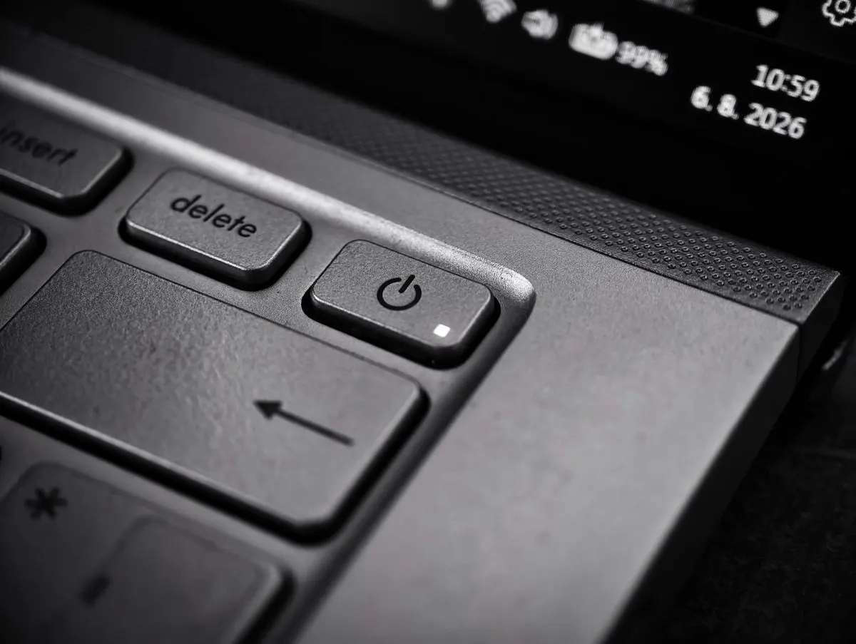 Zbliżenie przycisku zasilania laptopa z widocznym zegarem na ekranie — Komputer sam się wyłącza w spoczynku