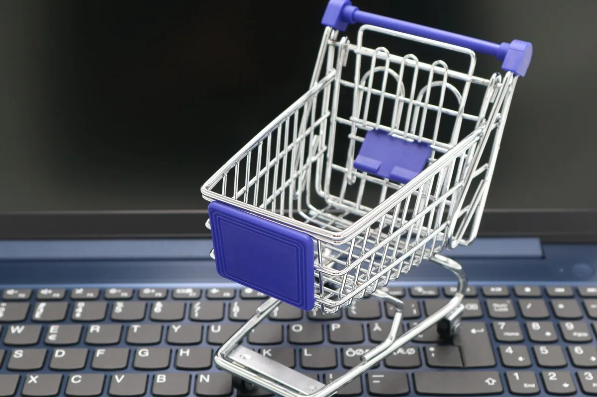A mini shopping cart placed on a laptop keyboard, symbolizing online shopping and digital retail.
