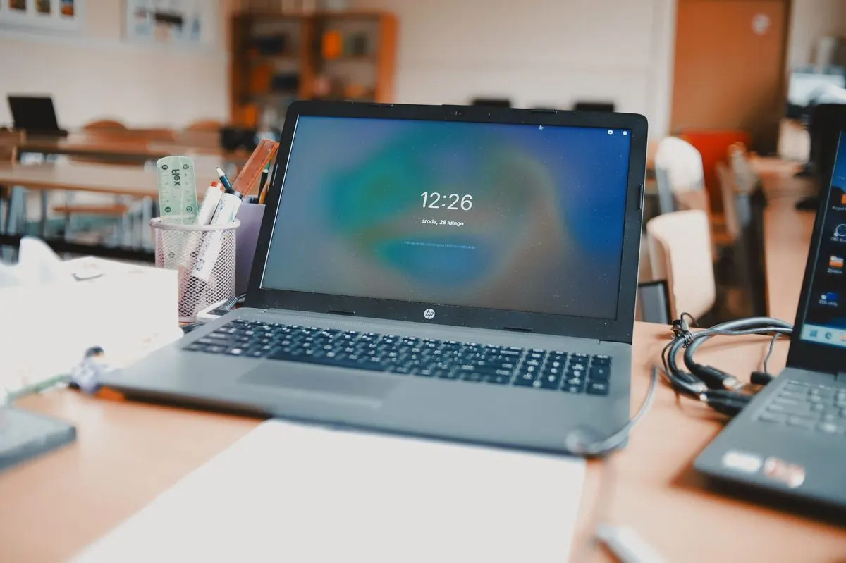 Laptop na biurku biurowym z pojemnikiem na długopisy i rośliną — Zgłoszenie awarii komputera dziecka przed nauką zdalną