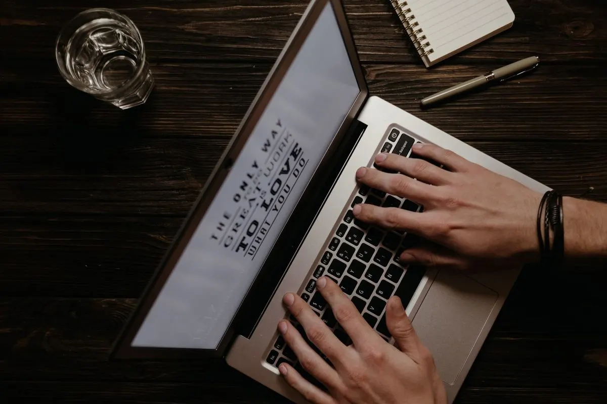 Dłonie piszące na laptopie obok śladu po rozlanym napoju — Zgłoszenie zalanego laptopa