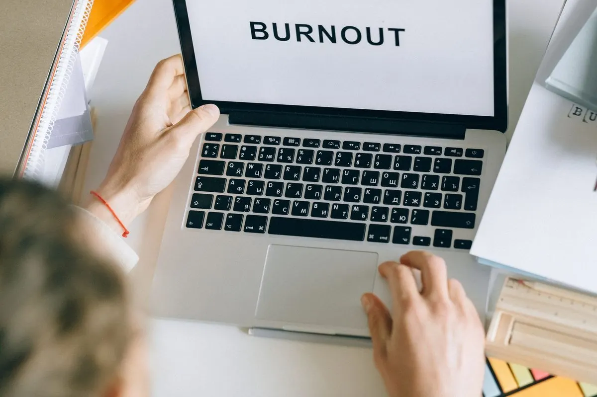 Ekran laptopa z napisem Burnout, dłoń wskazująca ekran — Zgłoszenie wolno działającego komputera domowego