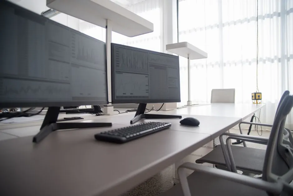 Rząd biurek z monitorami i ergonomicznymi krzesłami w nowoczesnym biurze — Bezpieczeństwo połączenia zdalnego — na co zwrócić uwagę
