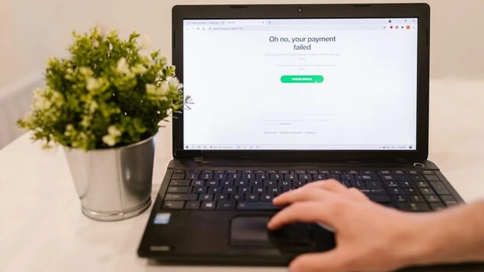 Laptop z komunikatem o nieudanej płatności na ekranie, dłoń na touchpadzie