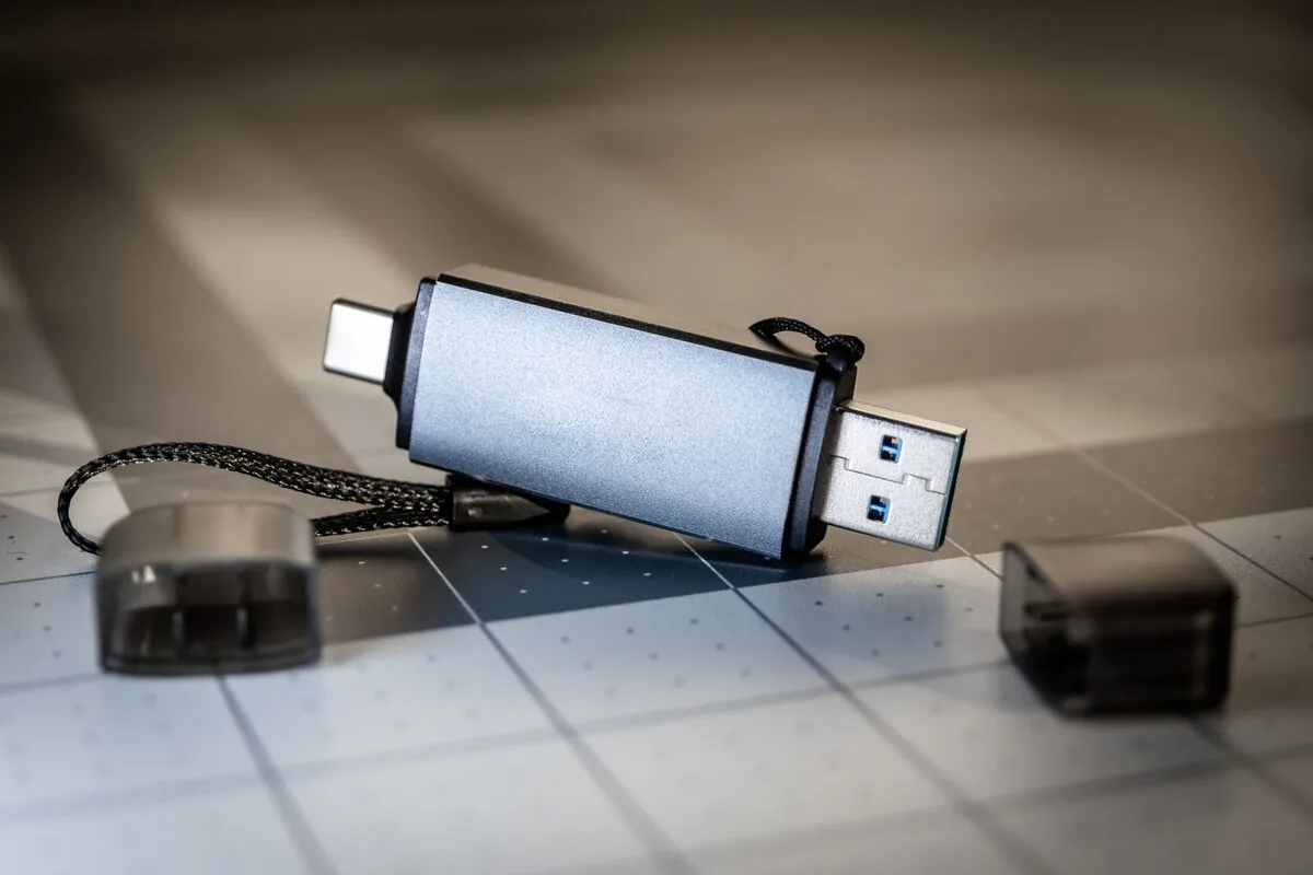 Dwustronny pendrive USB-A/USB-C leżący na blacie obok zaślepek