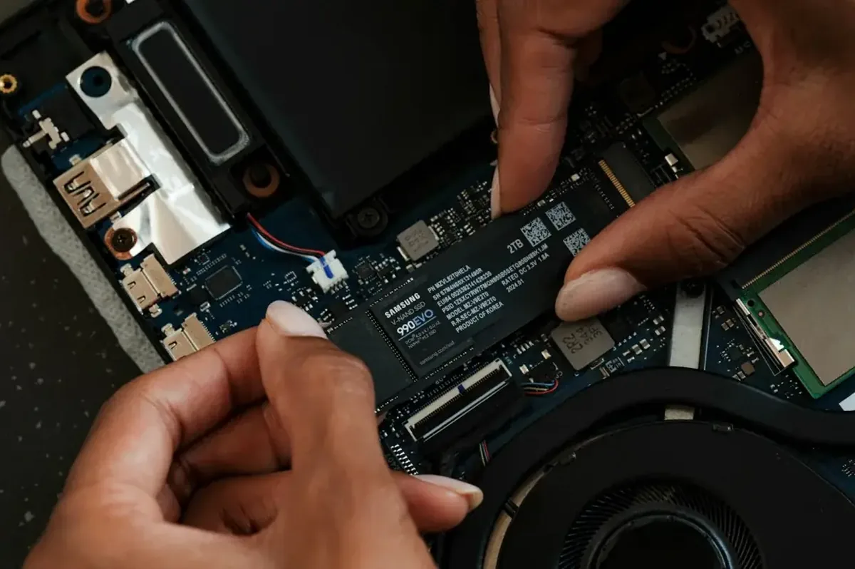 Dłonie wkręcające dysk SSD Samsung w laptopie