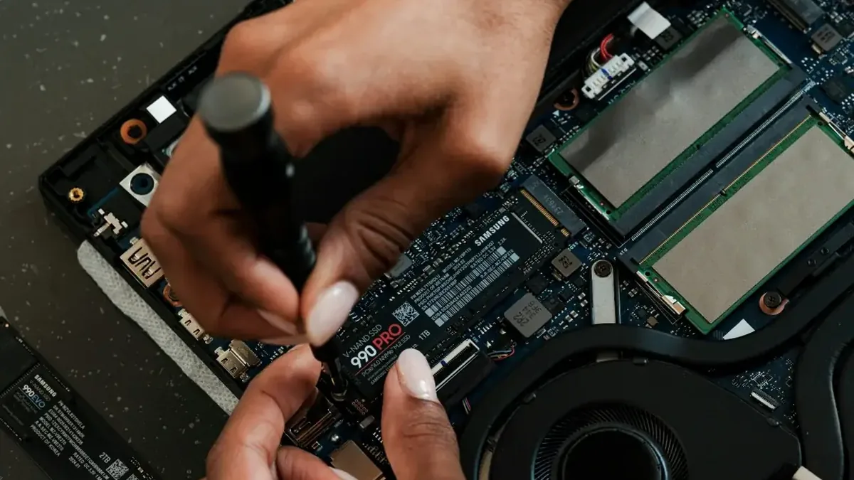 Dłonie wkręcające dysk SSD Samsung 990 PRO w laptopie