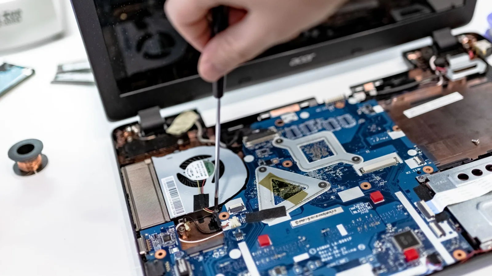 Dłoń ze śrubokrętem przy płycie głównej laptopa — Naprawa modułu TPM na płycie głównej laptopa