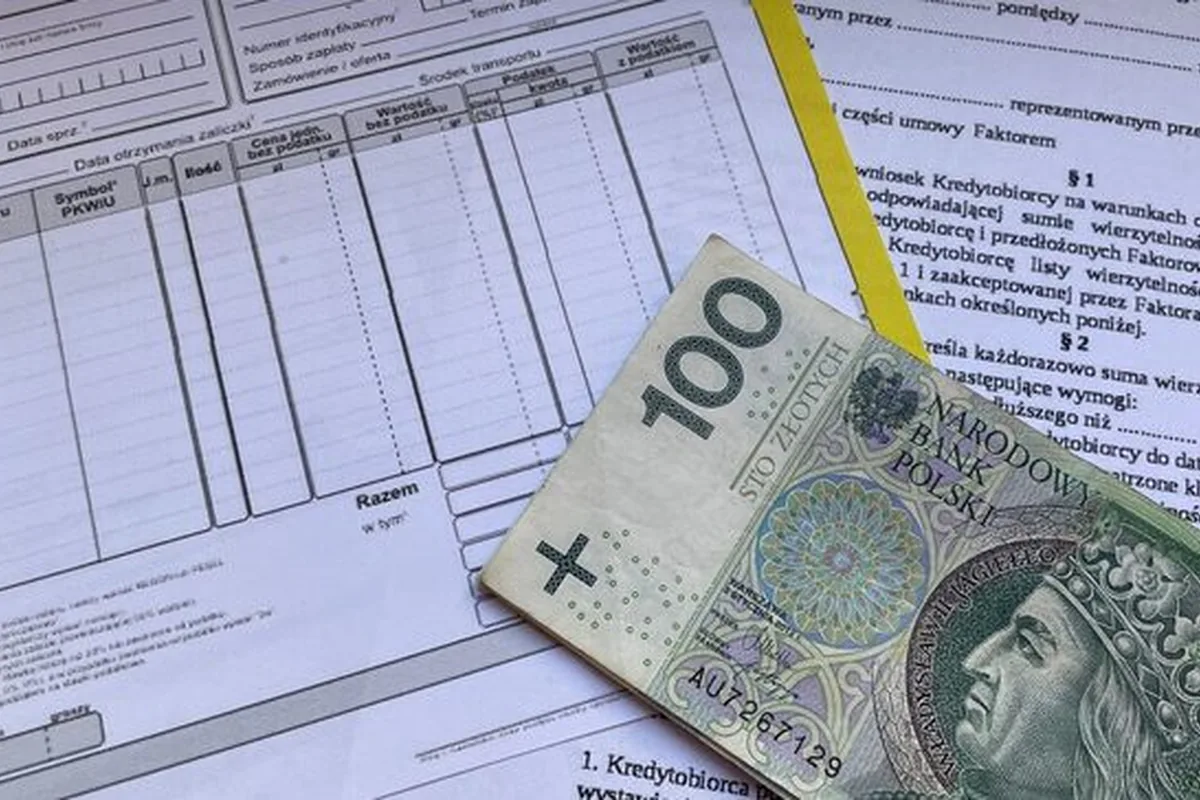 Faktura VAT i banknot 100 złotych na dokumentach